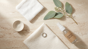 G23 titanium septum clicker, sterile saline spray and aftercare essentials laid out on cream travertine — SSZ Piercing