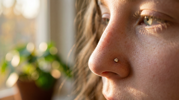 Close-up side-profile portrait of a young woman wearing a small G23 titanium nostril stud in golden-hour daylight — SSZ Piercing nose piercing guide