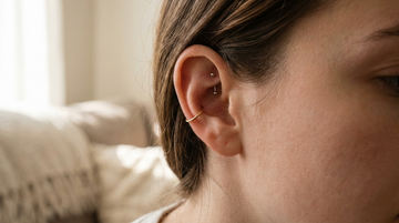 Close-up of a curated ear with a gold conch hoop and a rook curved barbell stacked together
