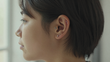 Close-up of a woman's ear wearing titanium flat back labret studs in helix and tragus piercings