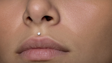 Medusa philtrum piercing — a single crystal titanium stud centered in the groove above the upper lip