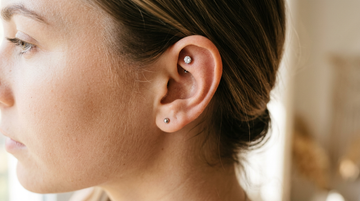 Close-up of an ear with a faux rook piercing — a single titanium gem stud in the flat cartilage above the rook fold