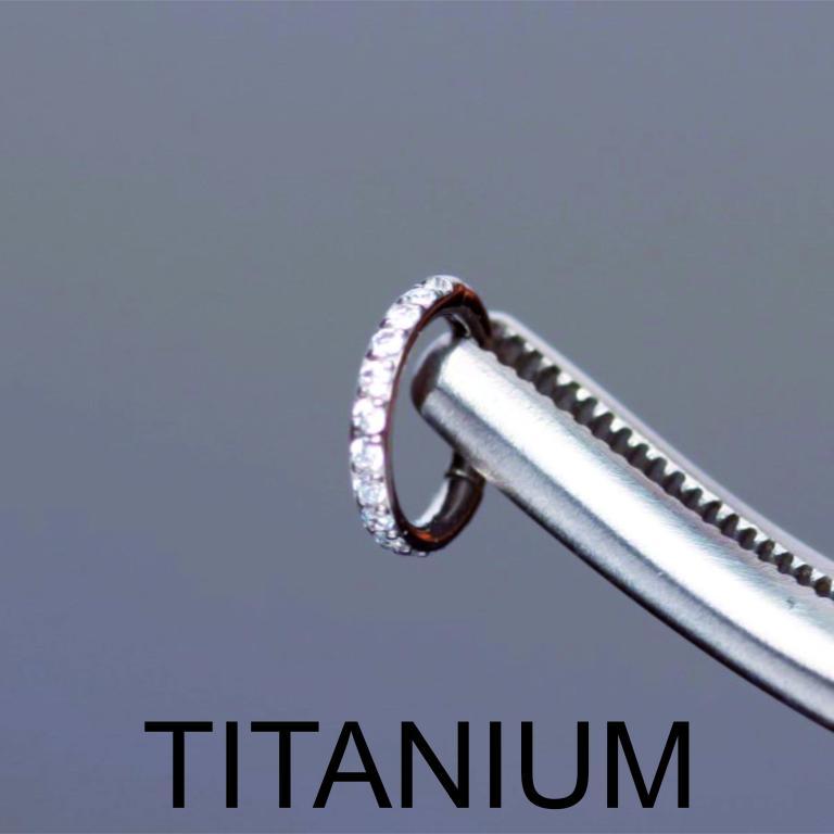 Macro shot of a silver titanium zircon clicker hoop ring held by
