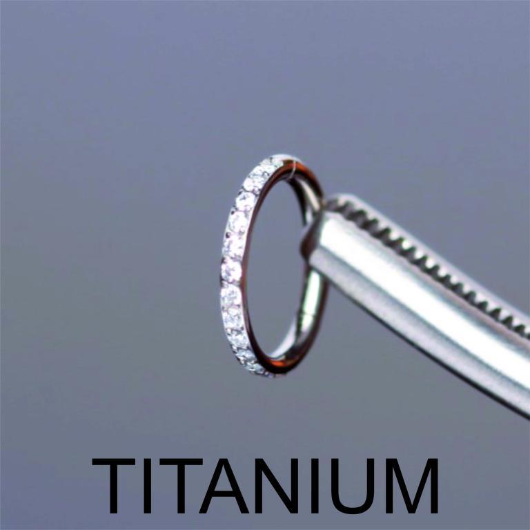 Close-up of a silver titanium zircon hinged clicker hoop ring emphasizing medical-grade