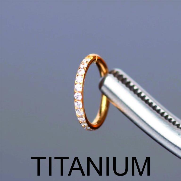 Macro shot of a gold titanium zircon clicker hoop ring held securely