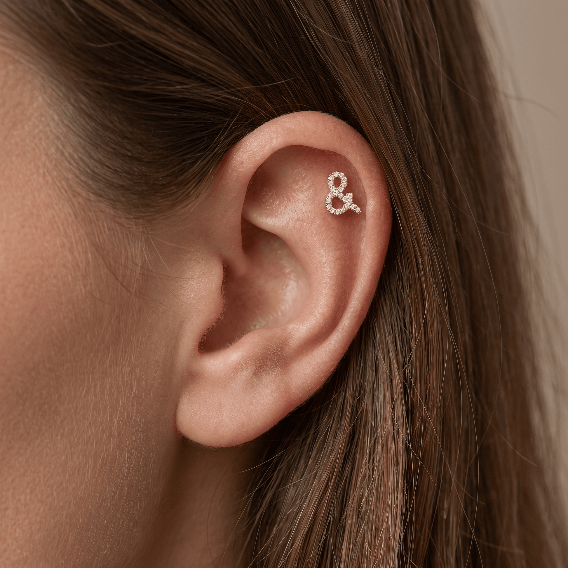 Gold ampersand zircon stud — flat helix piercing placement