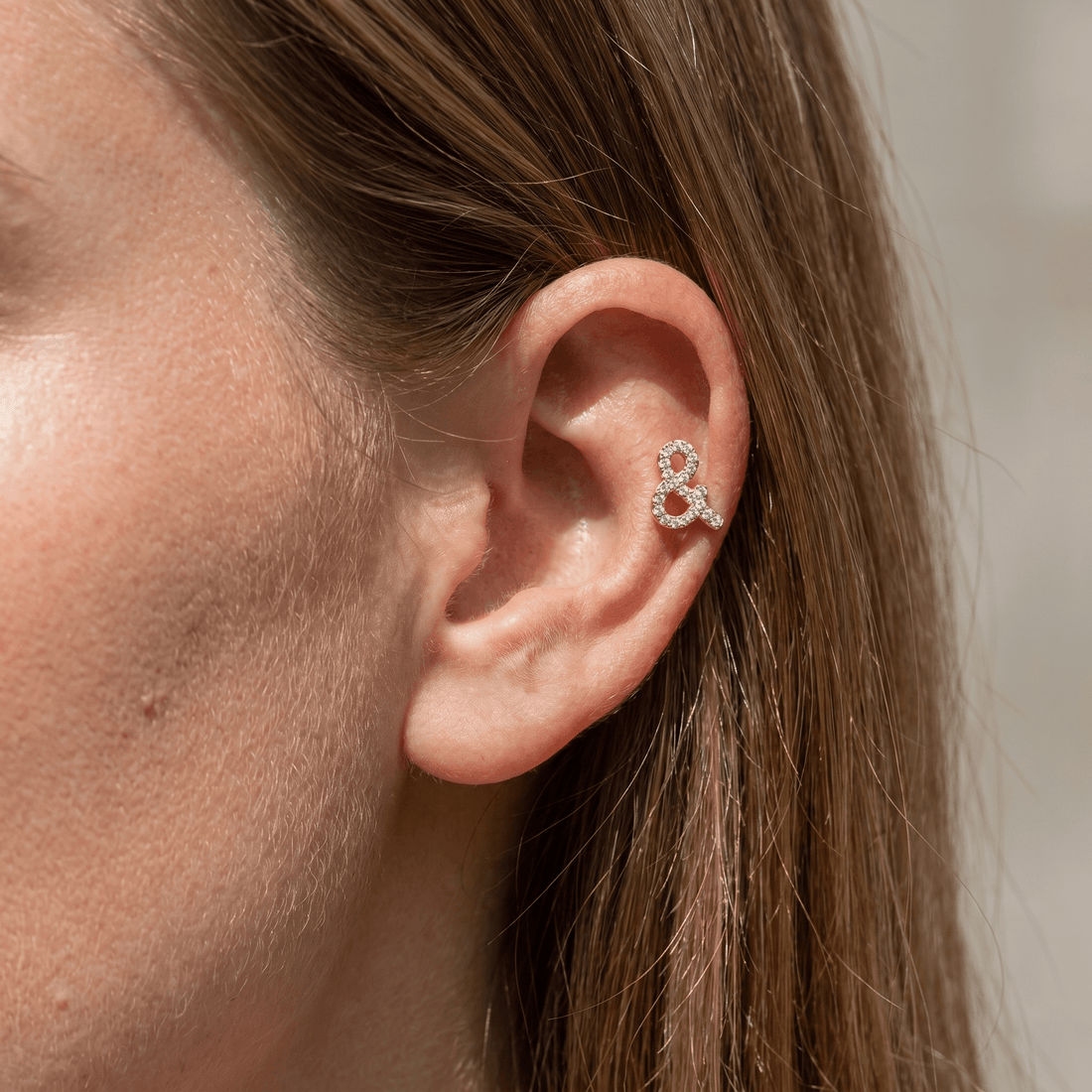 Silver ampersand zircon stud — mid helix piercing placement