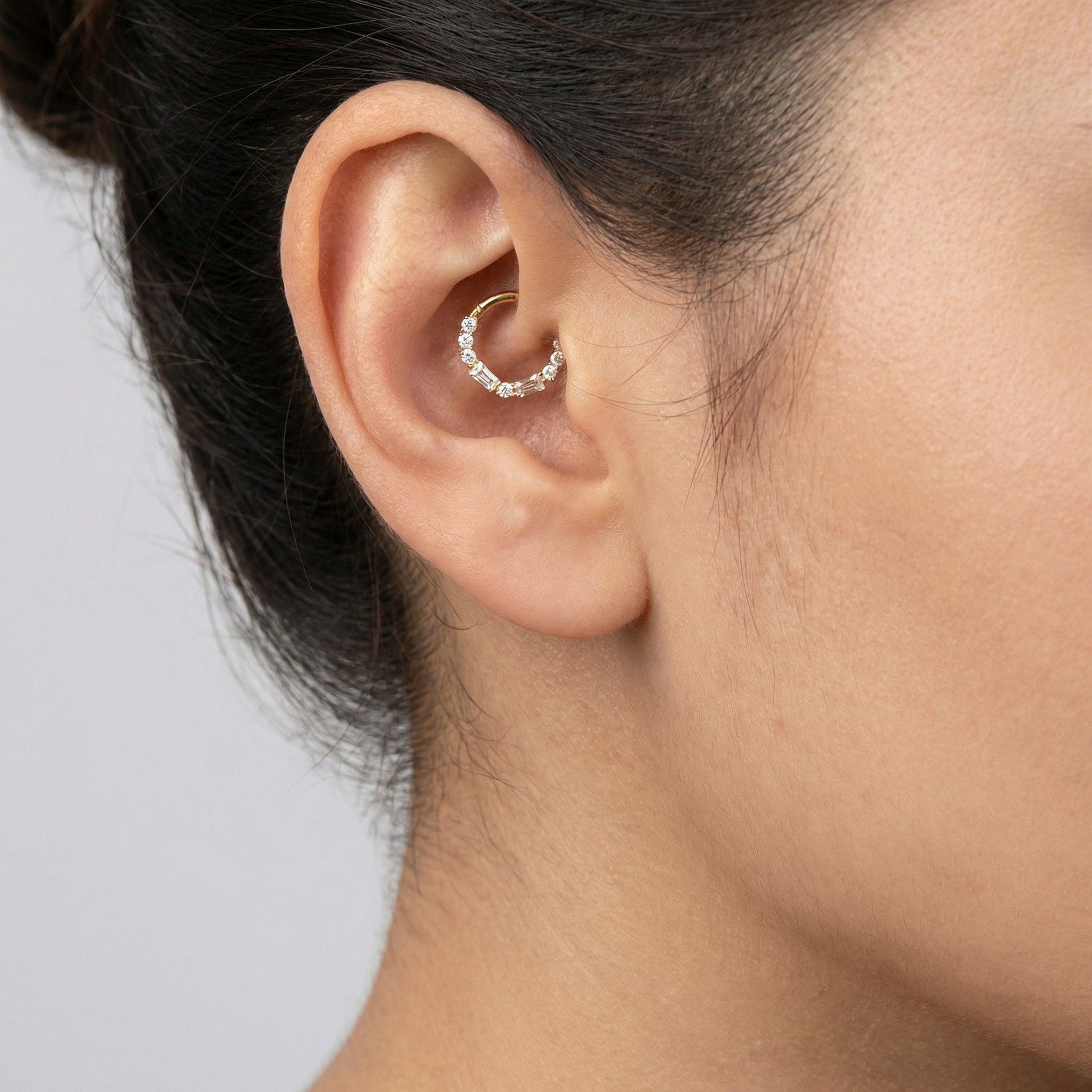 Close-up profile of a silver baguette and round zircon hinged clicker ring