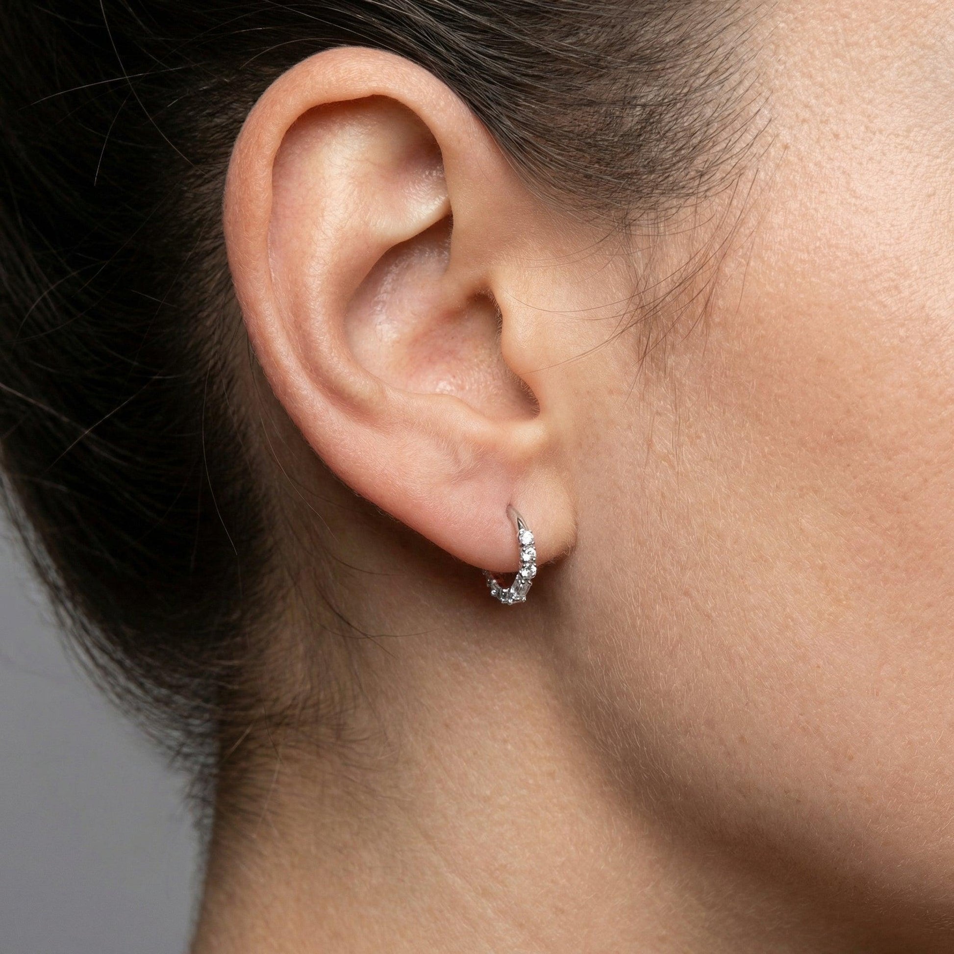 Close-up of a silver baguette and round zircon hinged clicker ring styled