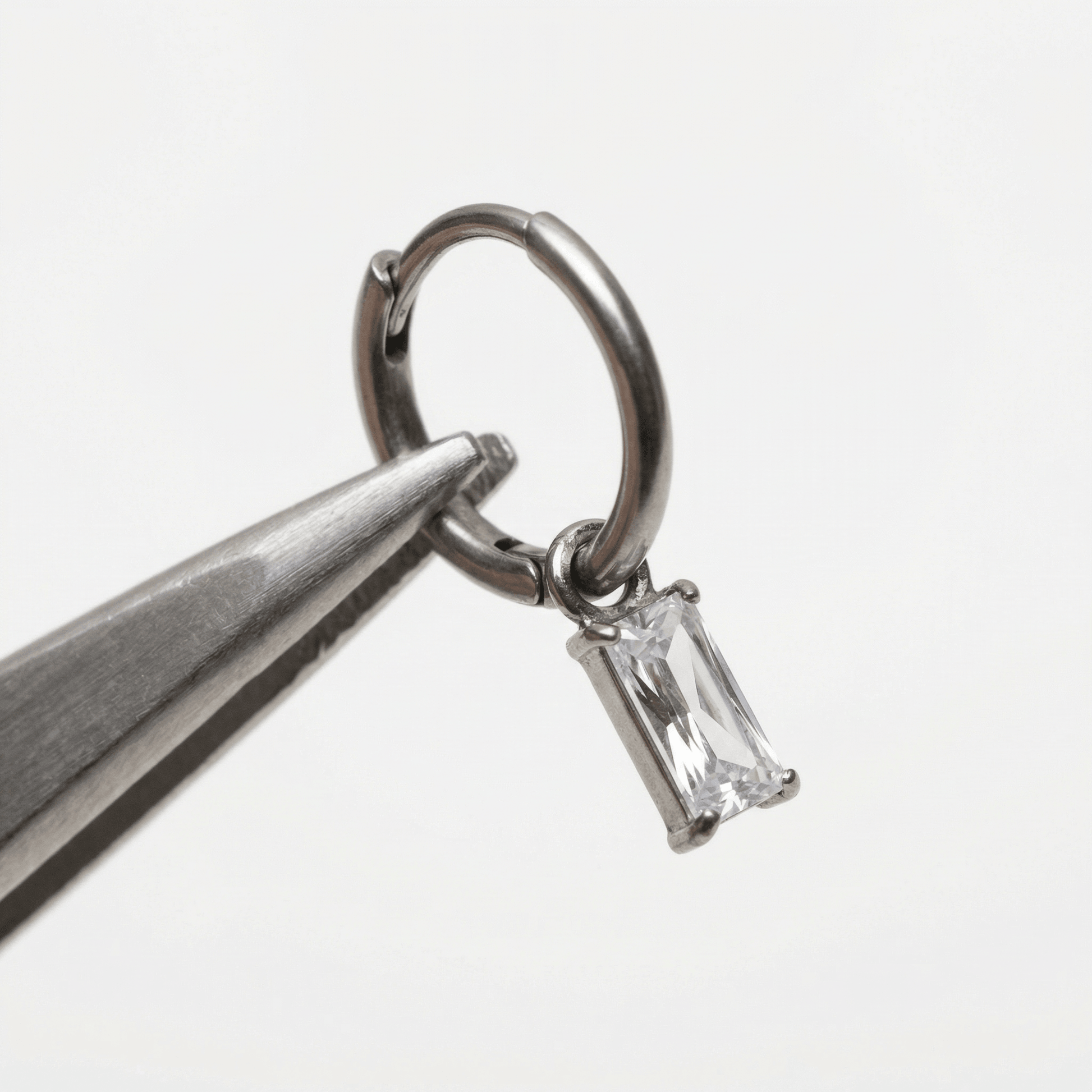 Baguette Front Helix Piercing - Tweezers holding open a