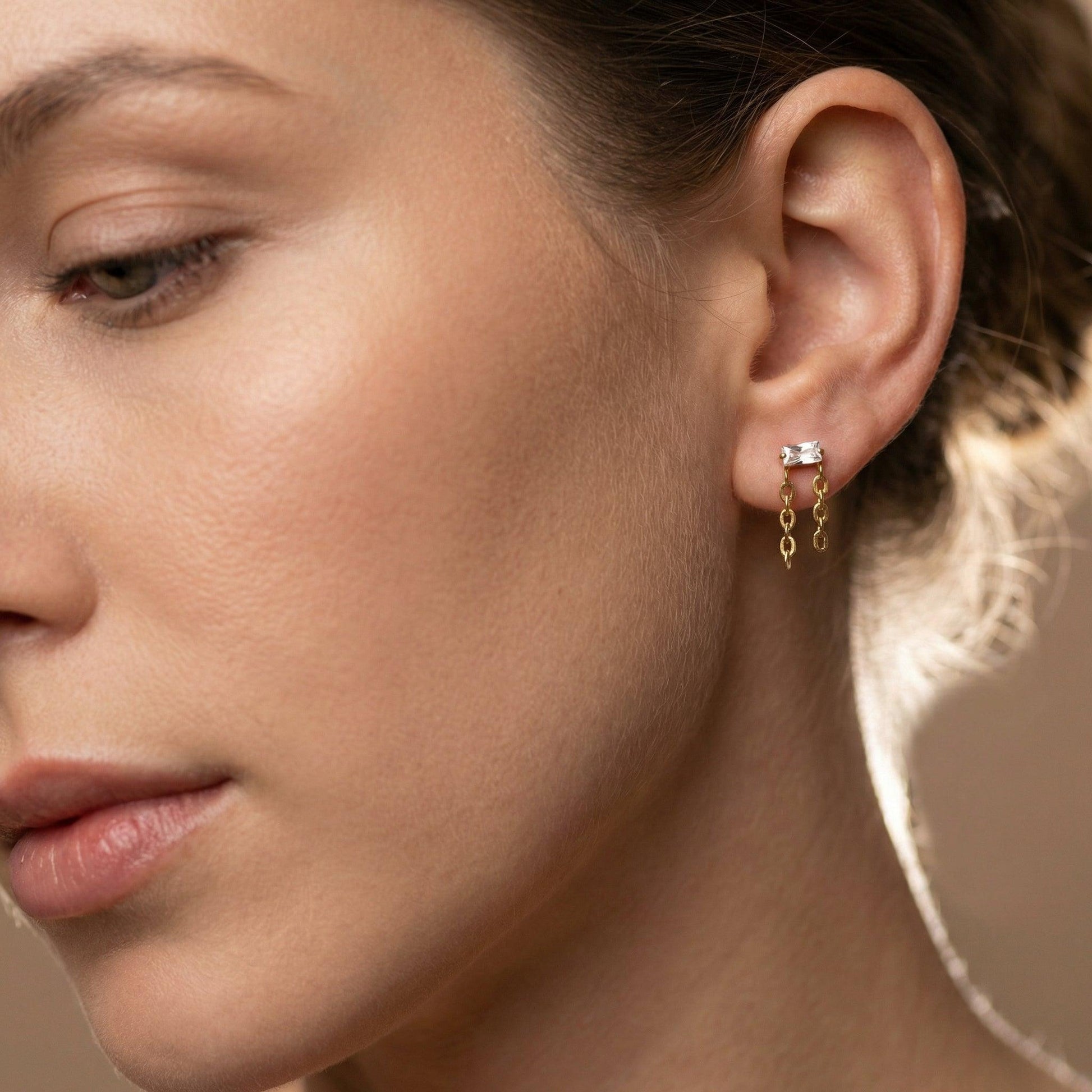 Front angle view of a gold titanium baguette zircon double chain piercing
