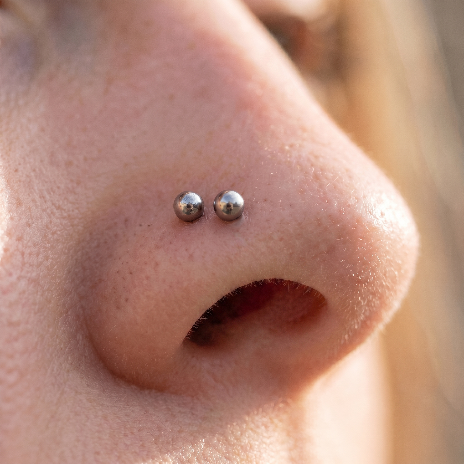 Two ball nose studs styled as a double nose piercing on one nostril