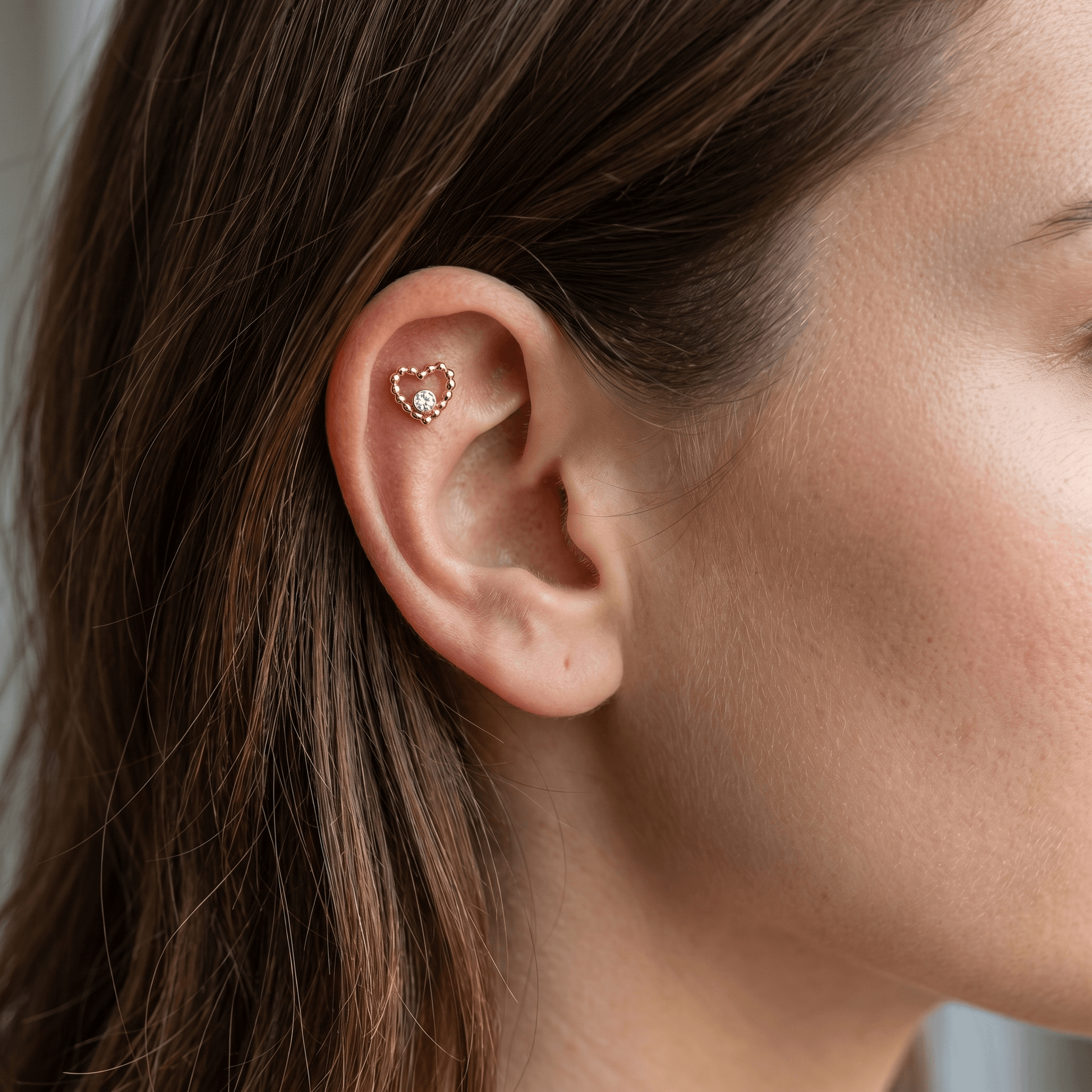 Gold titanium beaded heart piercing stud worn securely in a female piercing.