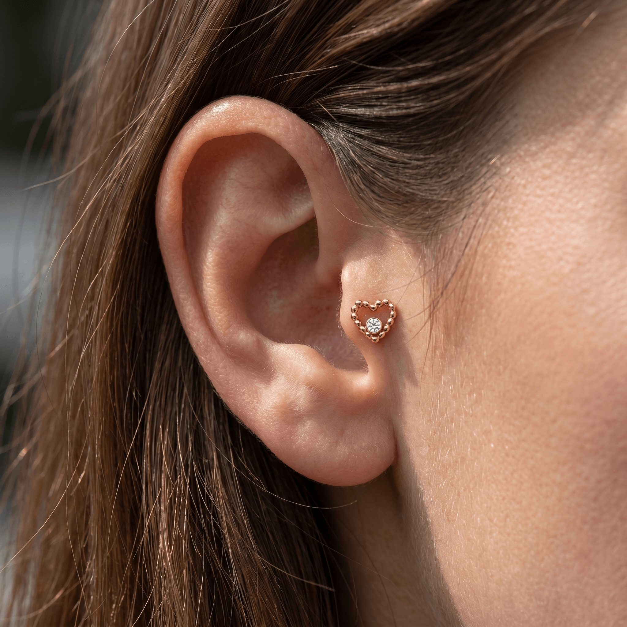 Gold titanium beaded heart stud worn perfectly inside a female piercing.