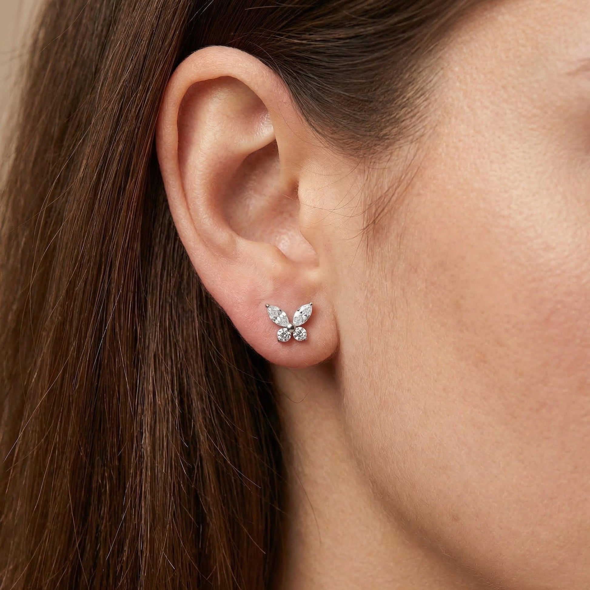 Silver titanium butterfly piercing stud worn in a female .