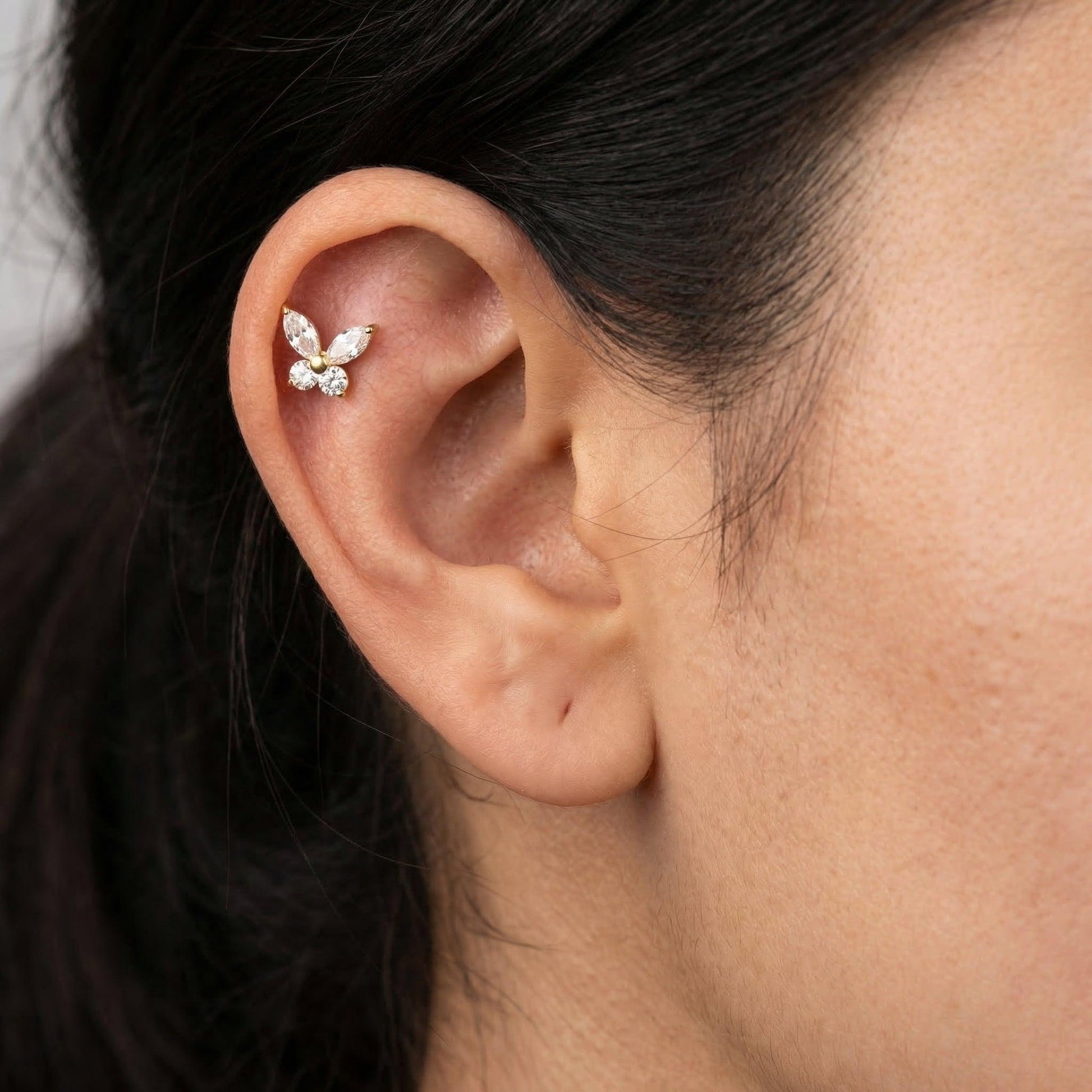 Gold titanium butterfly piercing stud worn in a female ear.