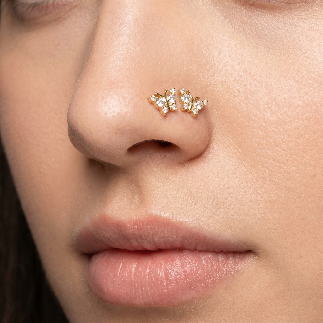 Two butterfly nose studs styled as a double nose piercing on one nostril