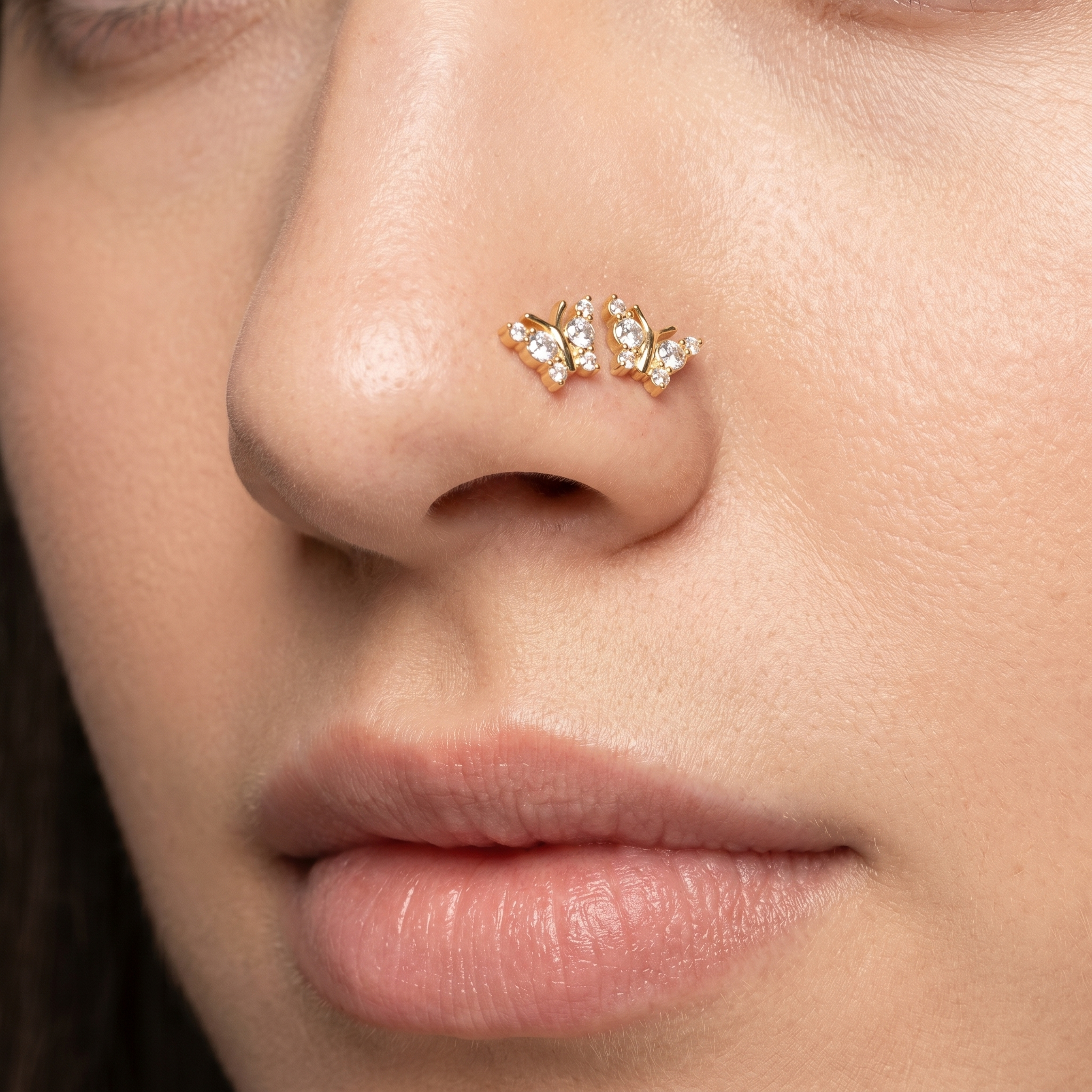 Two butterfly nose studs styled as a double nose piercing on one nostril