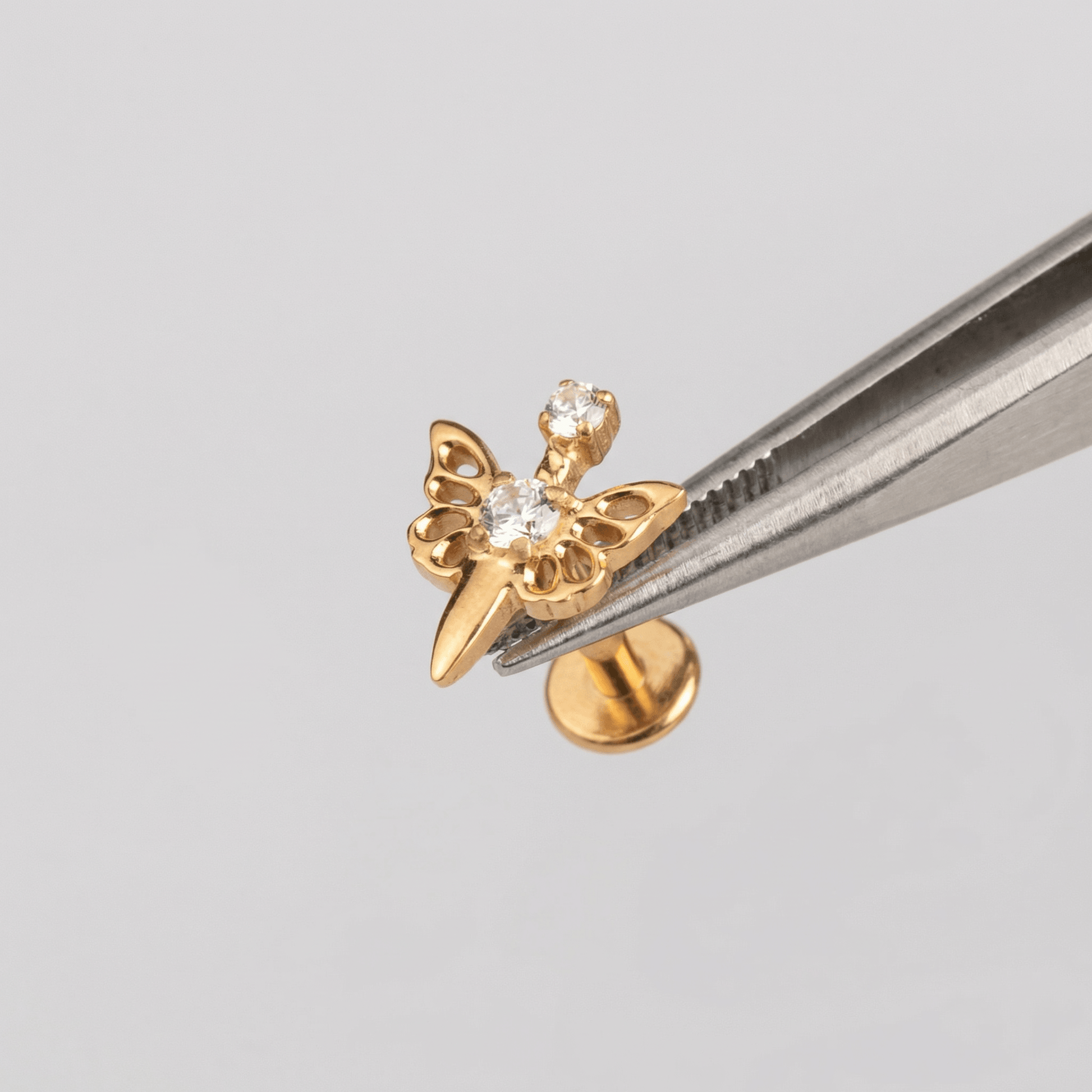 Butterfly Front Helix Piercing - Tweezers holding a gold