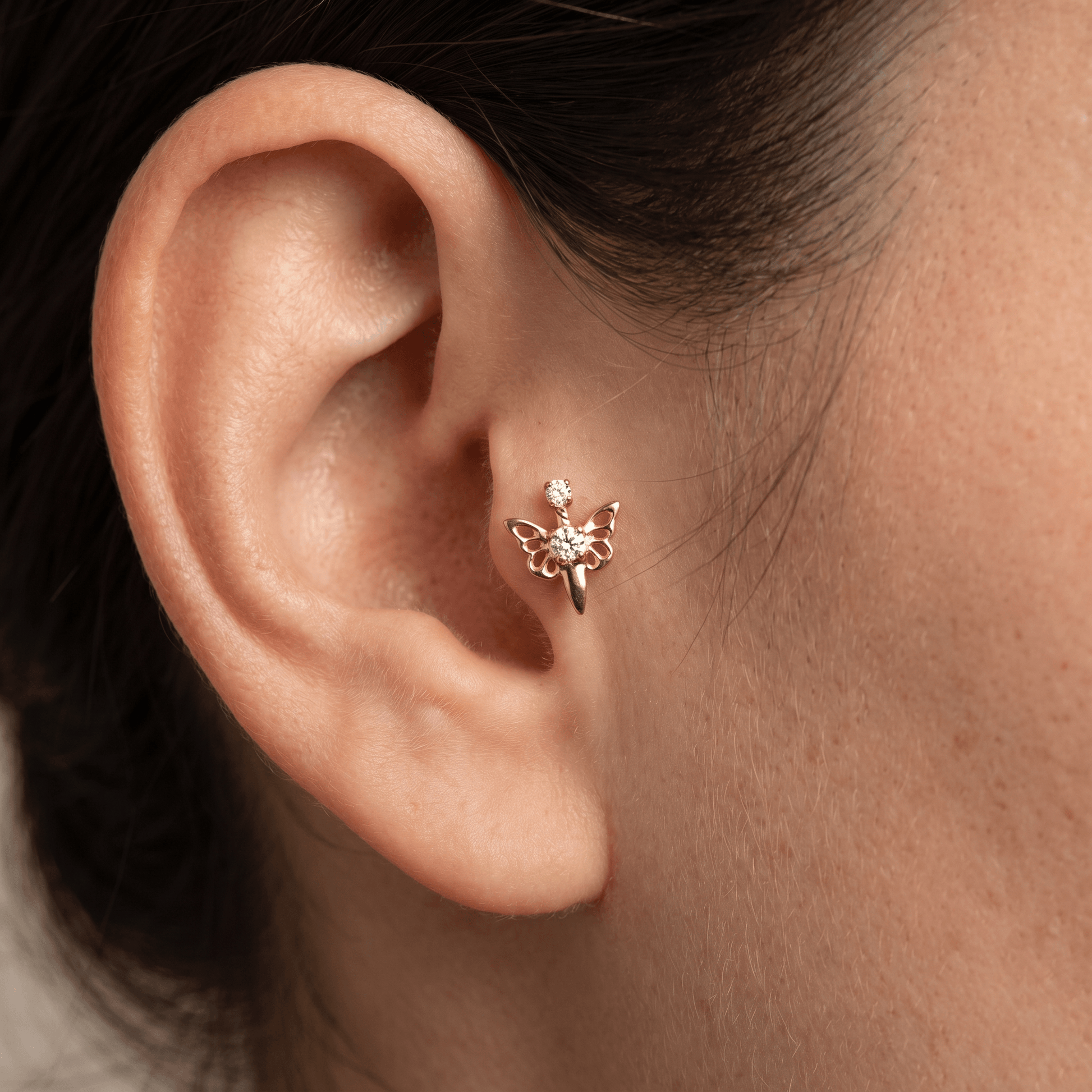 Gold titanium butterfly zircon piercing stud worn elegantly in a female piercing.
