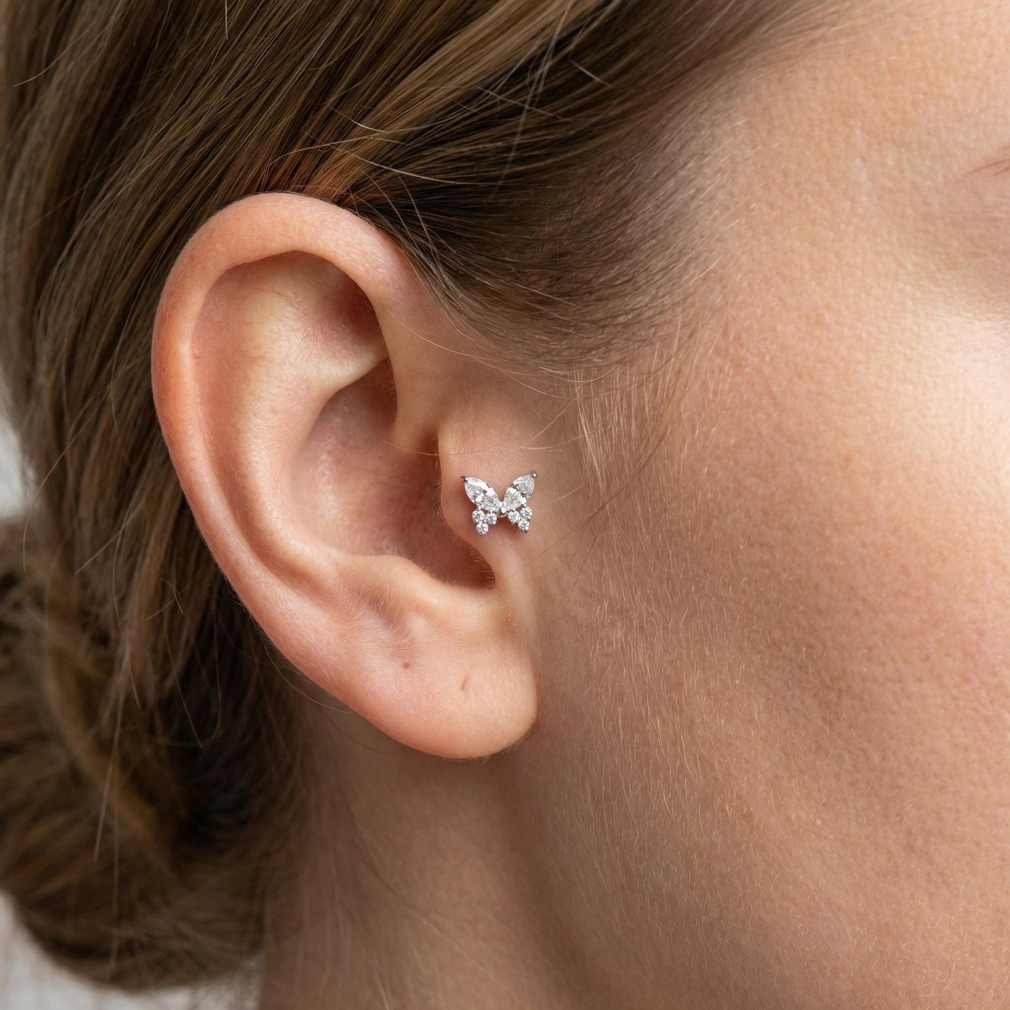 Silver titanium butterfly zircon piercing stud worn securely in a female .
