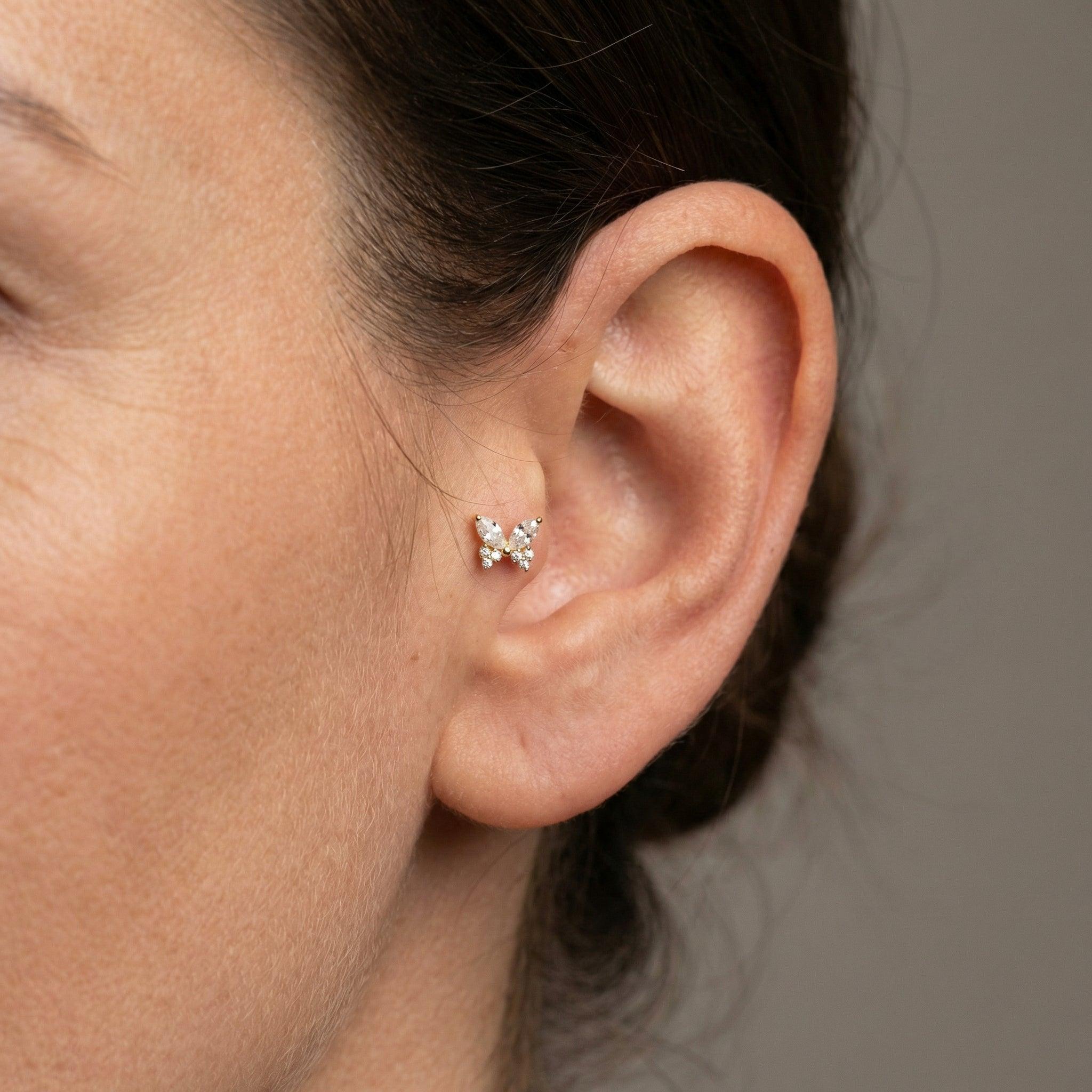 Gold titanium butterfly zircon piercing stud worn securely in a female .