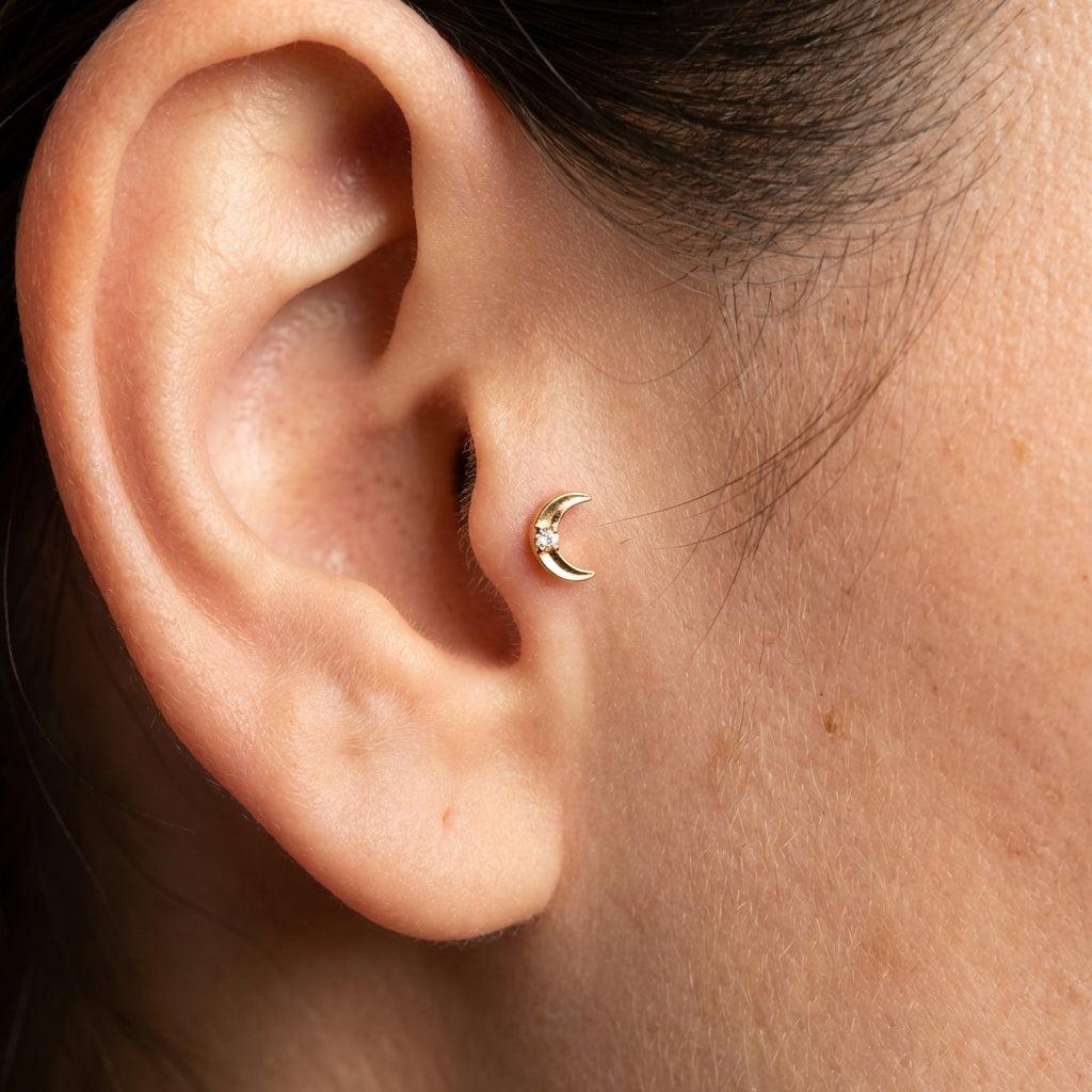 Gold titanium crescent moon piercing stud worn perfectly in a female piercing.