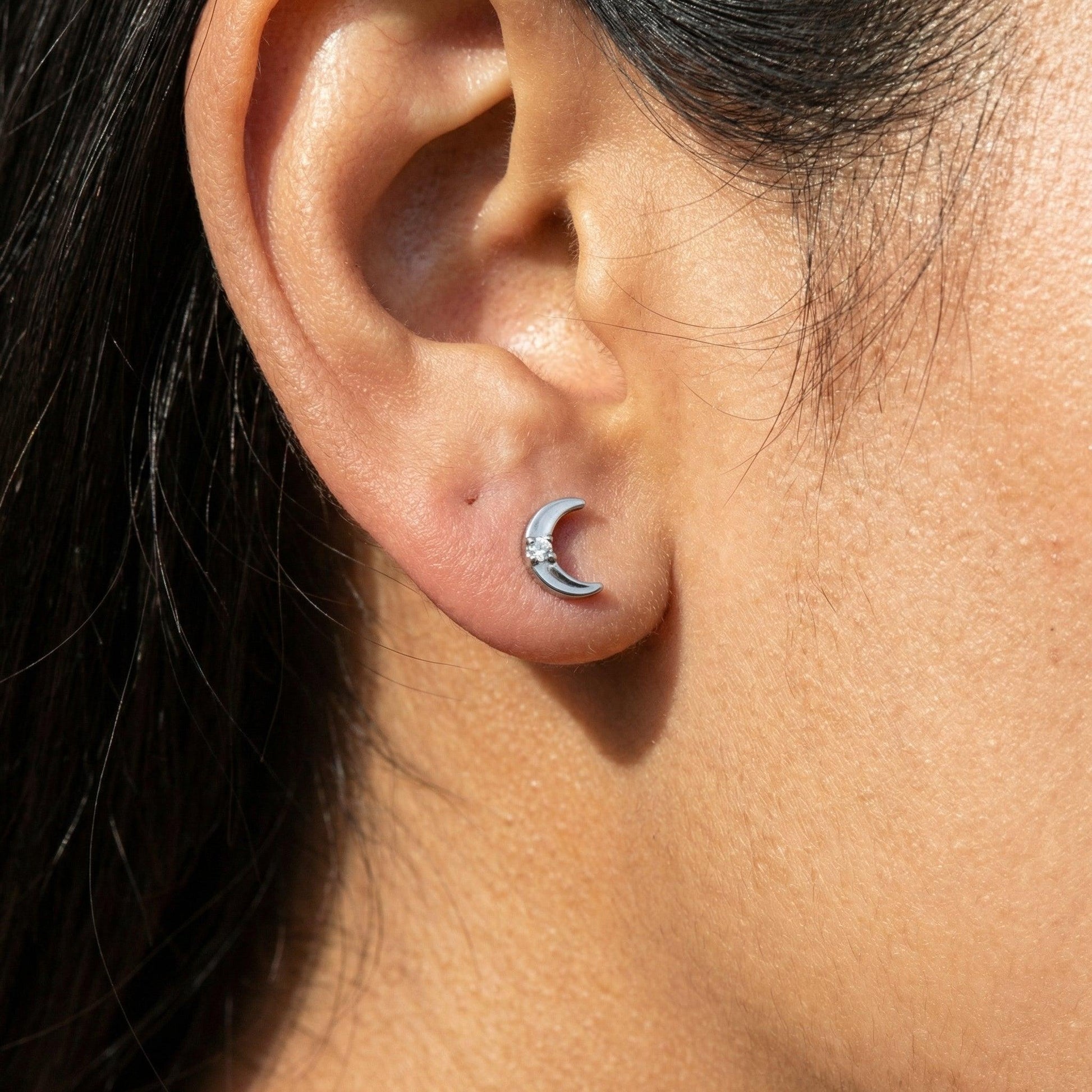 Silver titanium crescent moon piercing stud worn beautifully in a female .