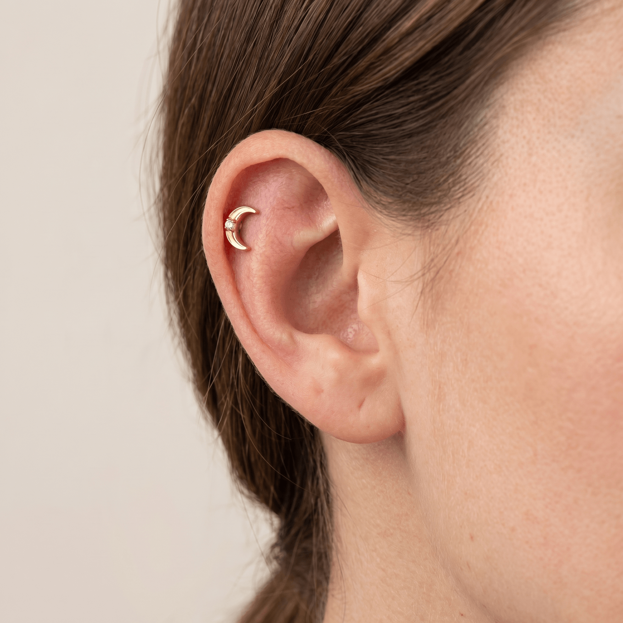 Gold titanium crescent moon stud with a single zircon worn elegantly in