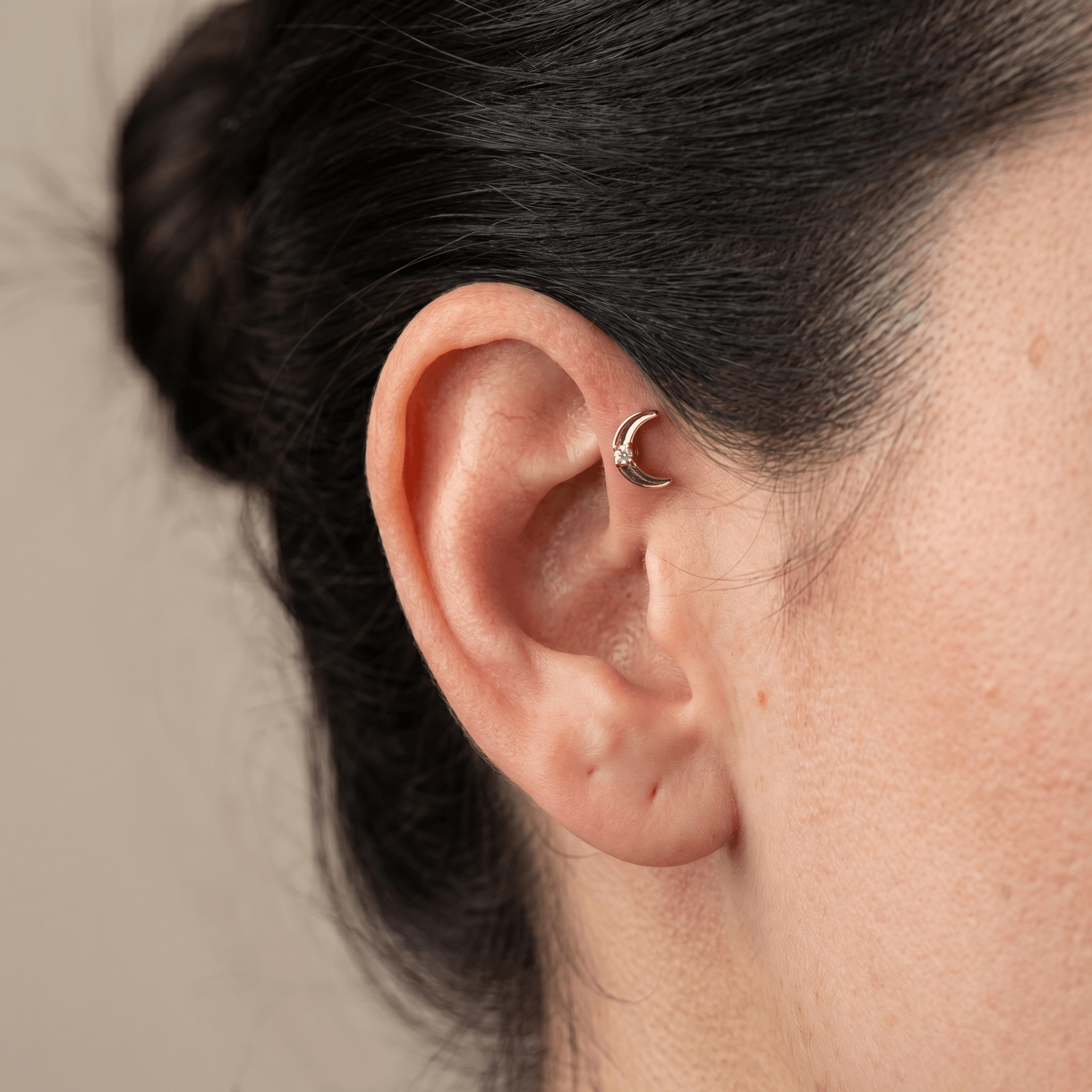 Gold titanium crescent moon piercing stud worn securely in a female piercing.
