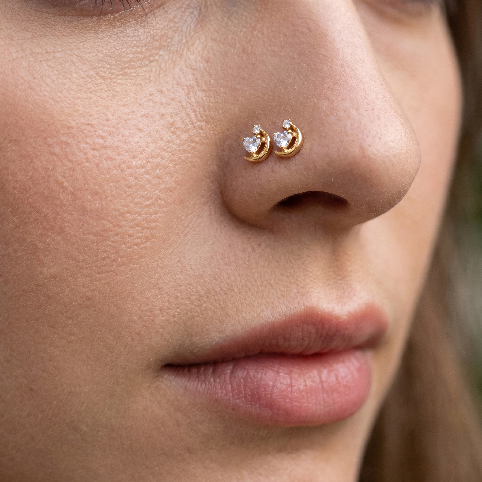 Two crescent moon nose studs styled as a double nose piercing on one nostril