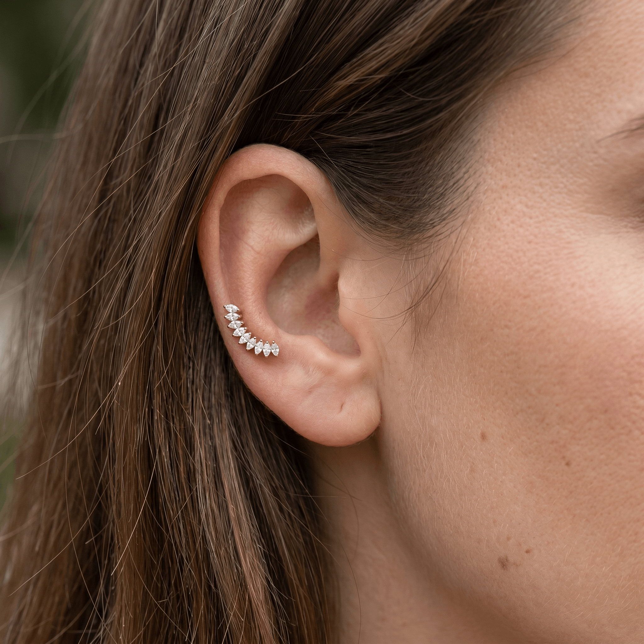 Silver crown leaf stud following the natural curve of the ear.