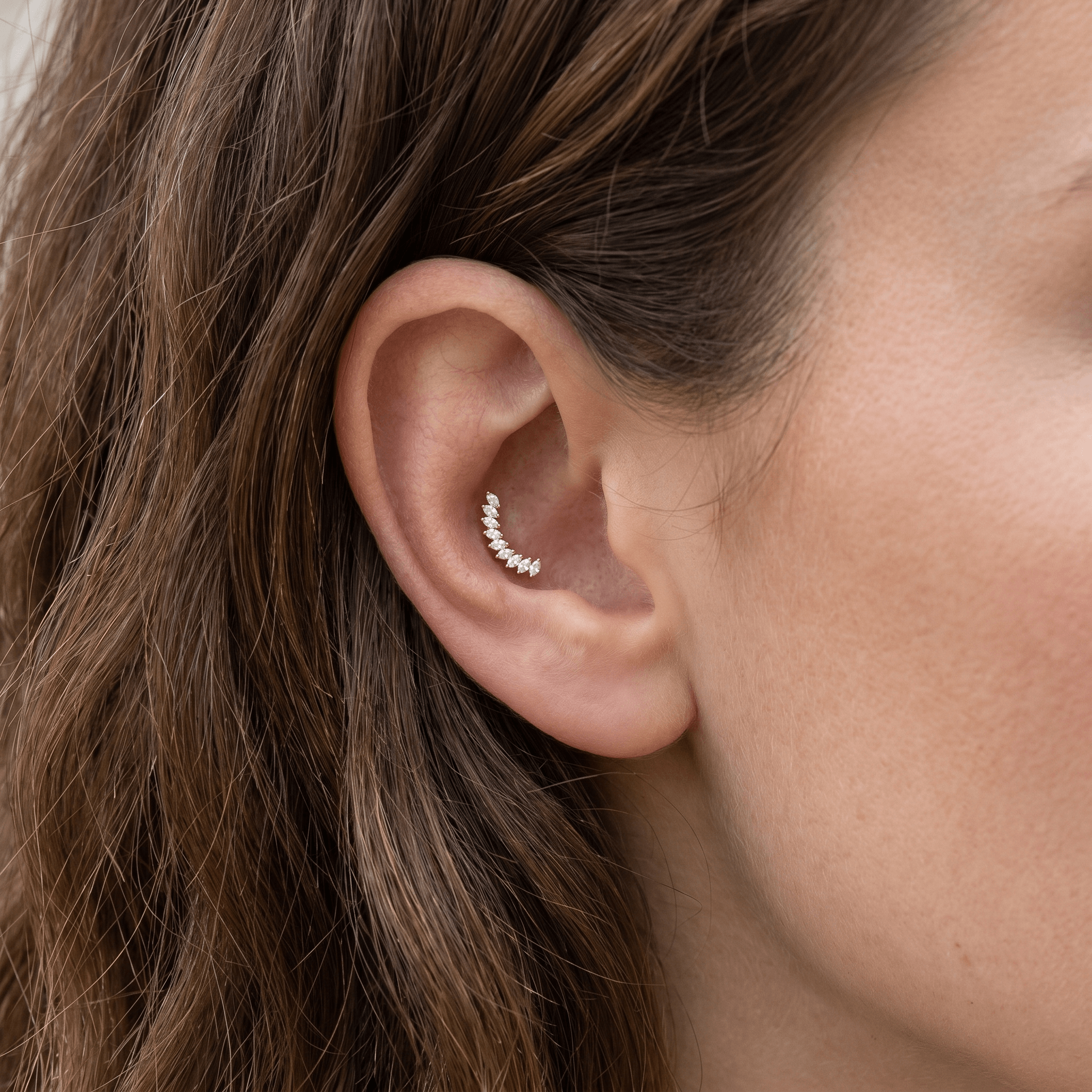 Gold climbing leaf ear stud worn in a conch ear placement.