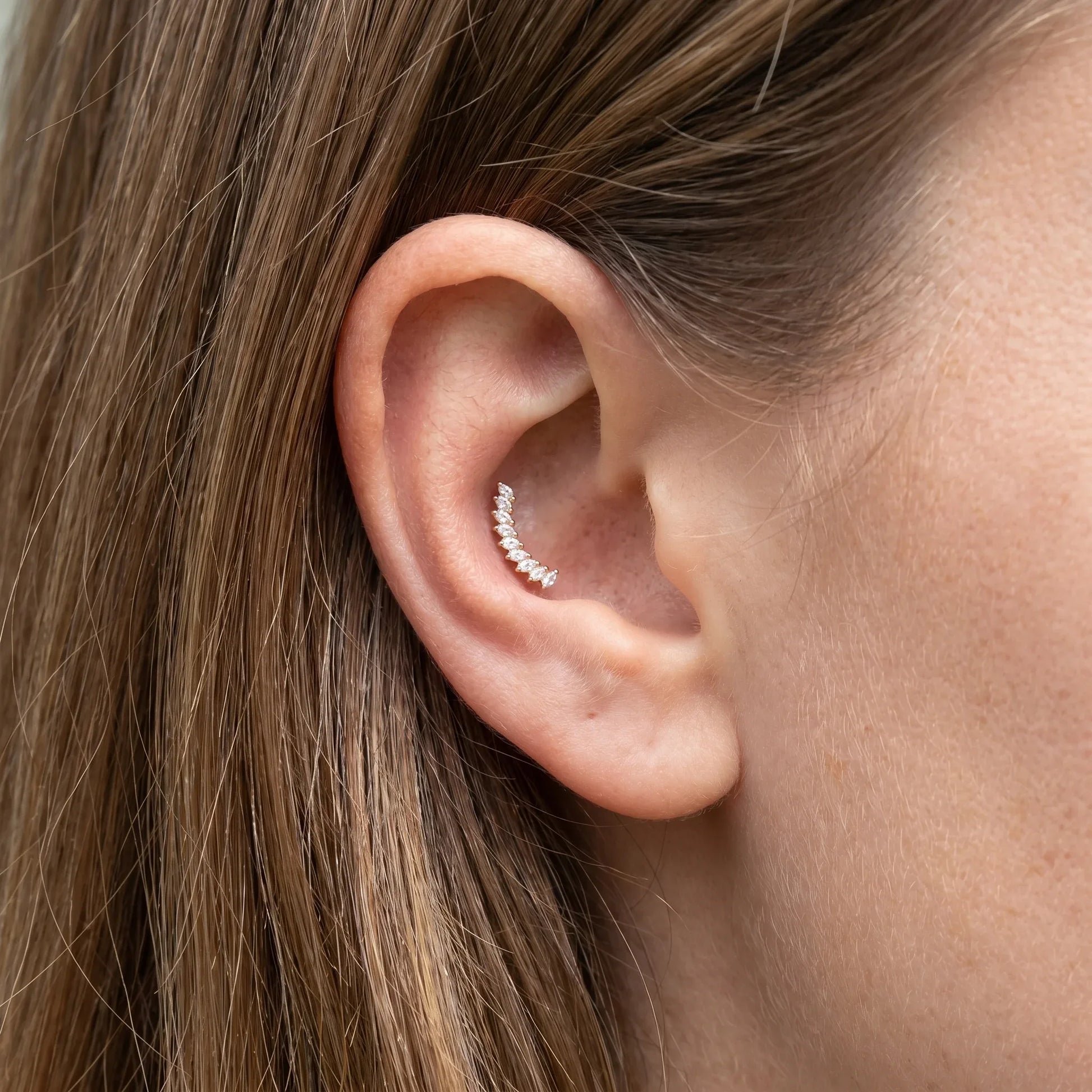 Gold crown leaf outer stud worn beautifully in a female ear.