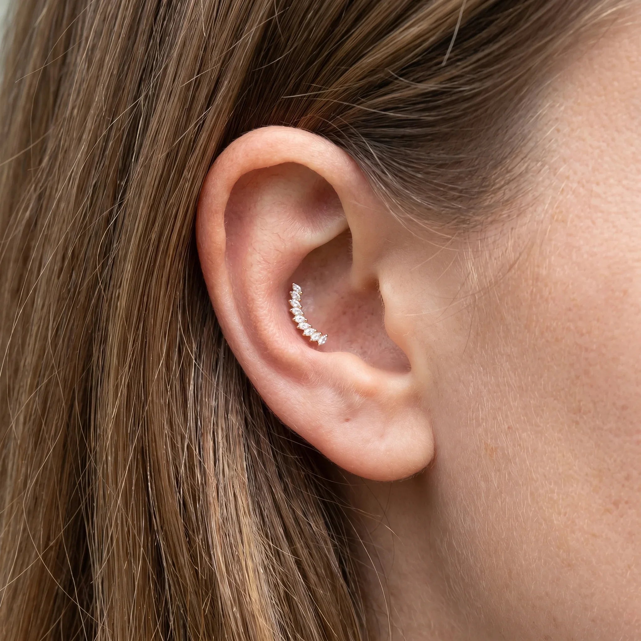Gold crown leaf outer stud worn beautifully in a female ear.