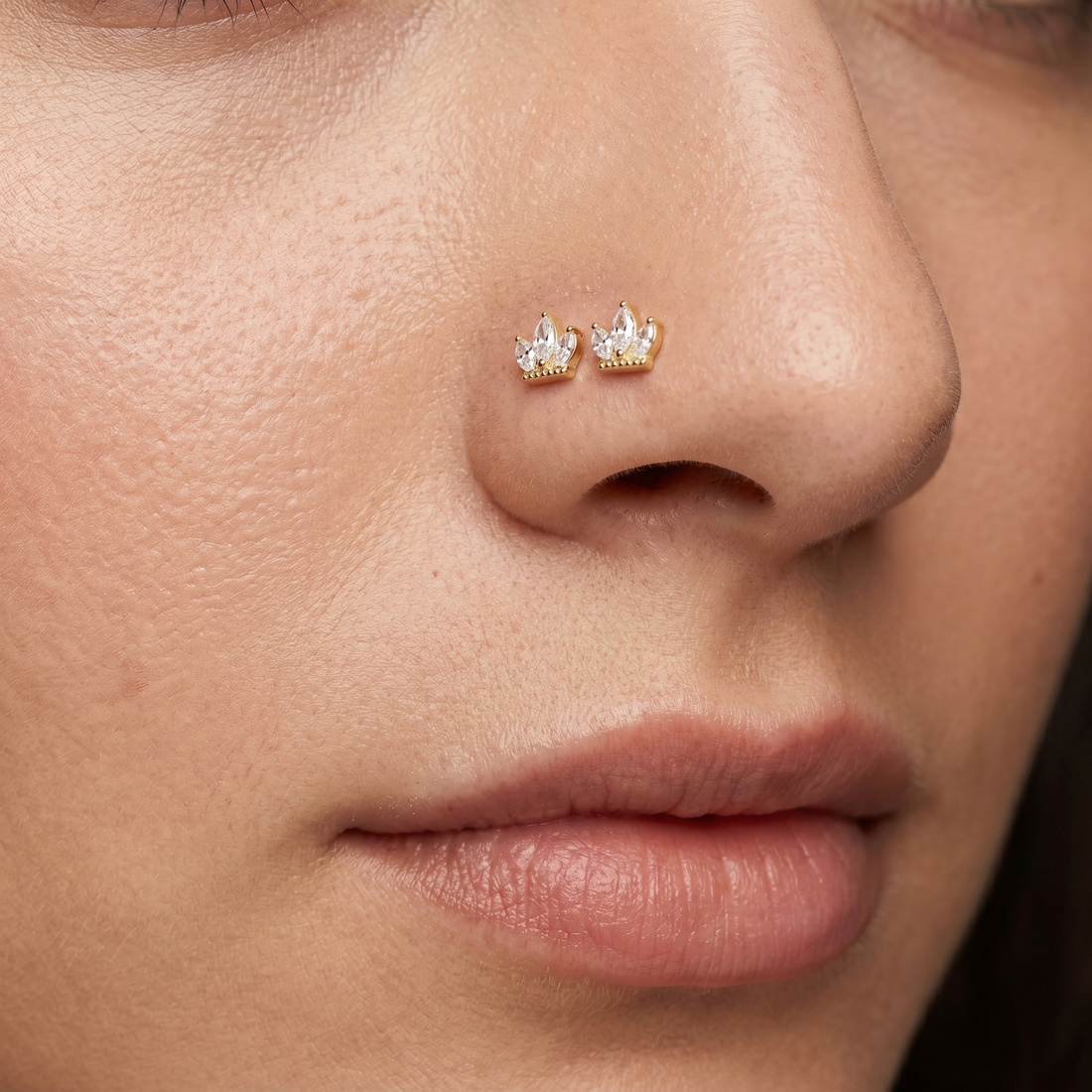 Two crown nose studs styled as a double nose piercing on one nostril