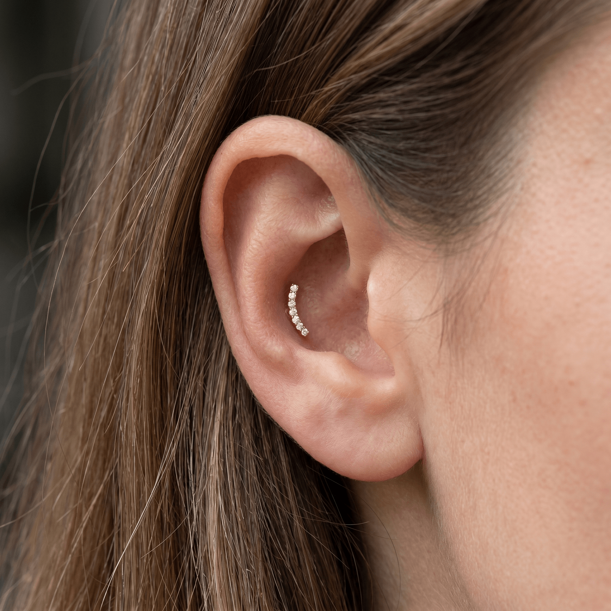 Gold hypoallergenic ear ring worn in an piercing.