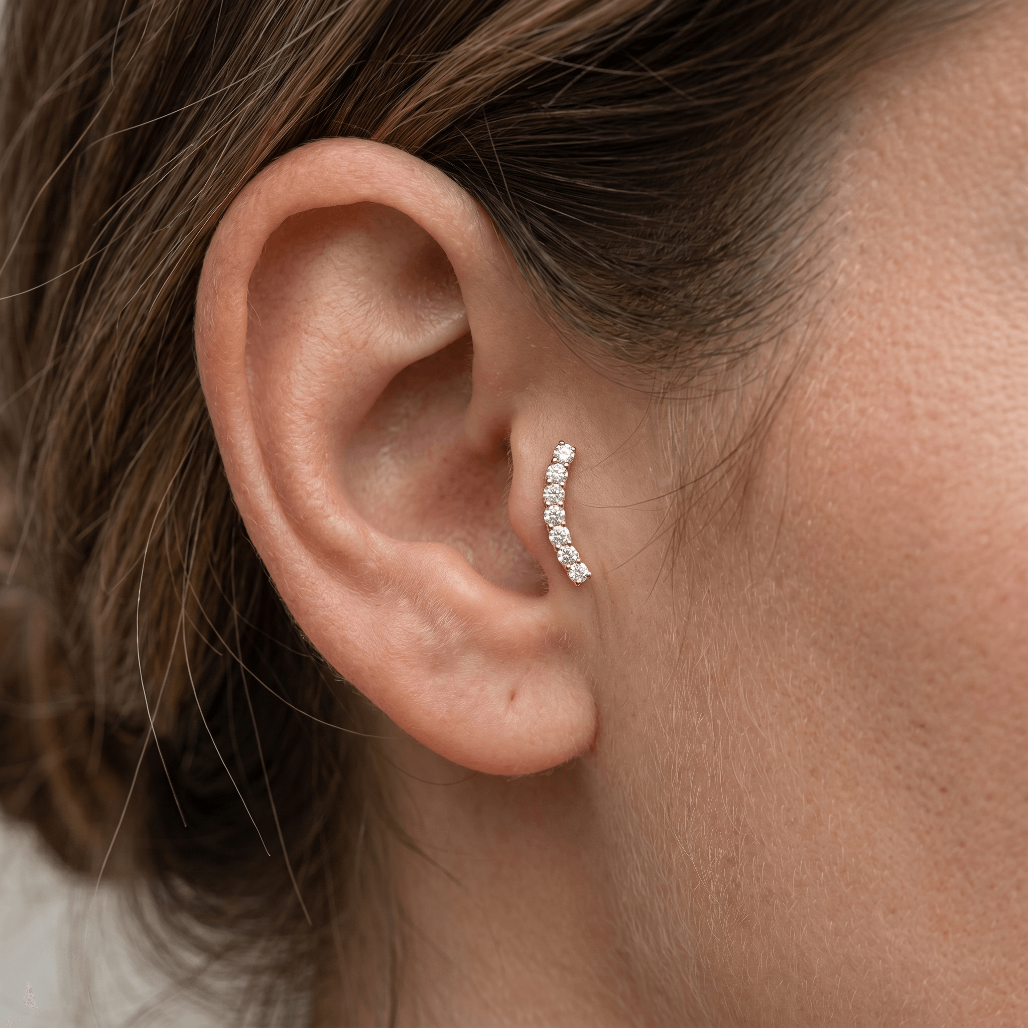 Gold curved bar stud worn in a female ear.