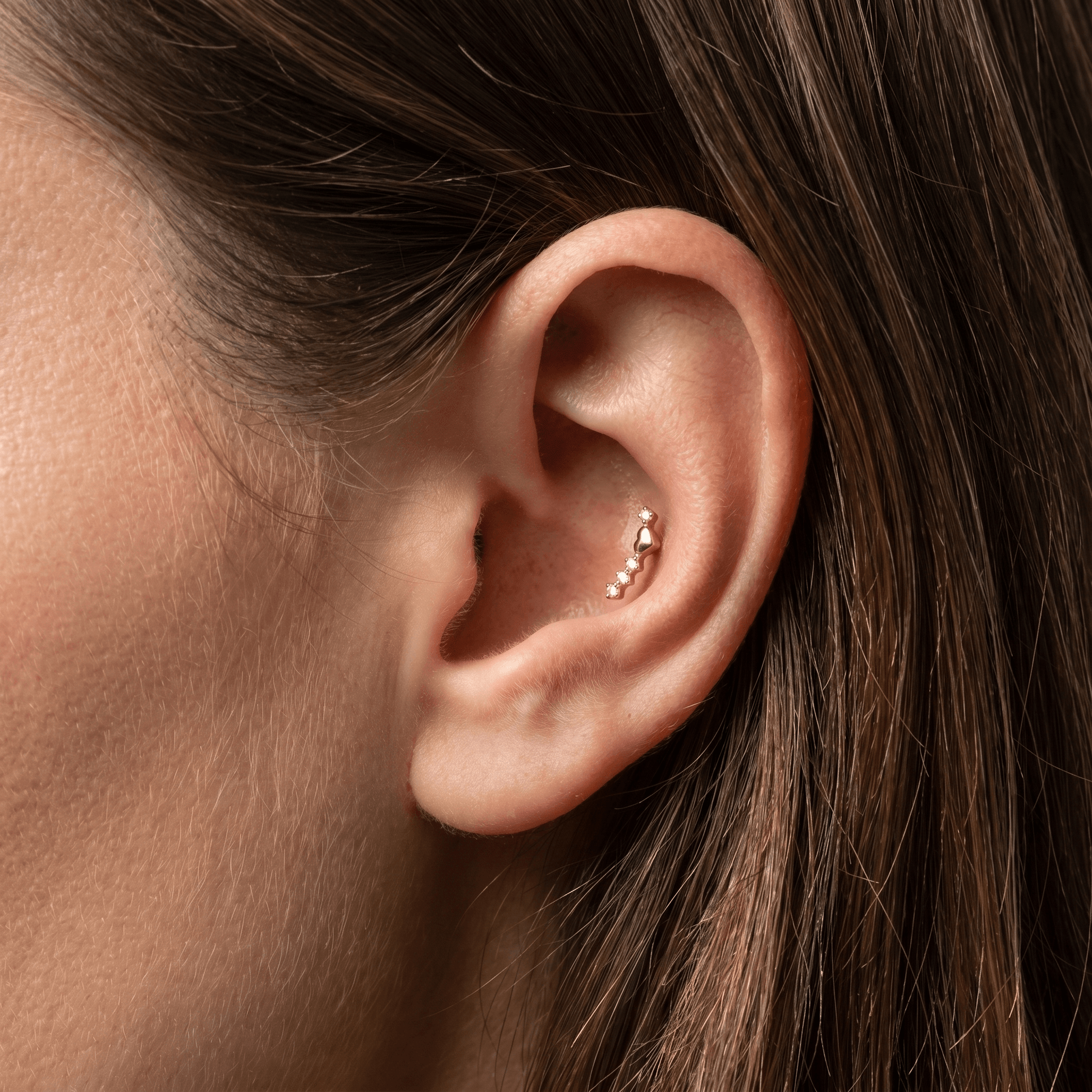 Gold titanium curved zircon piercing stud worn in a female piercing.
