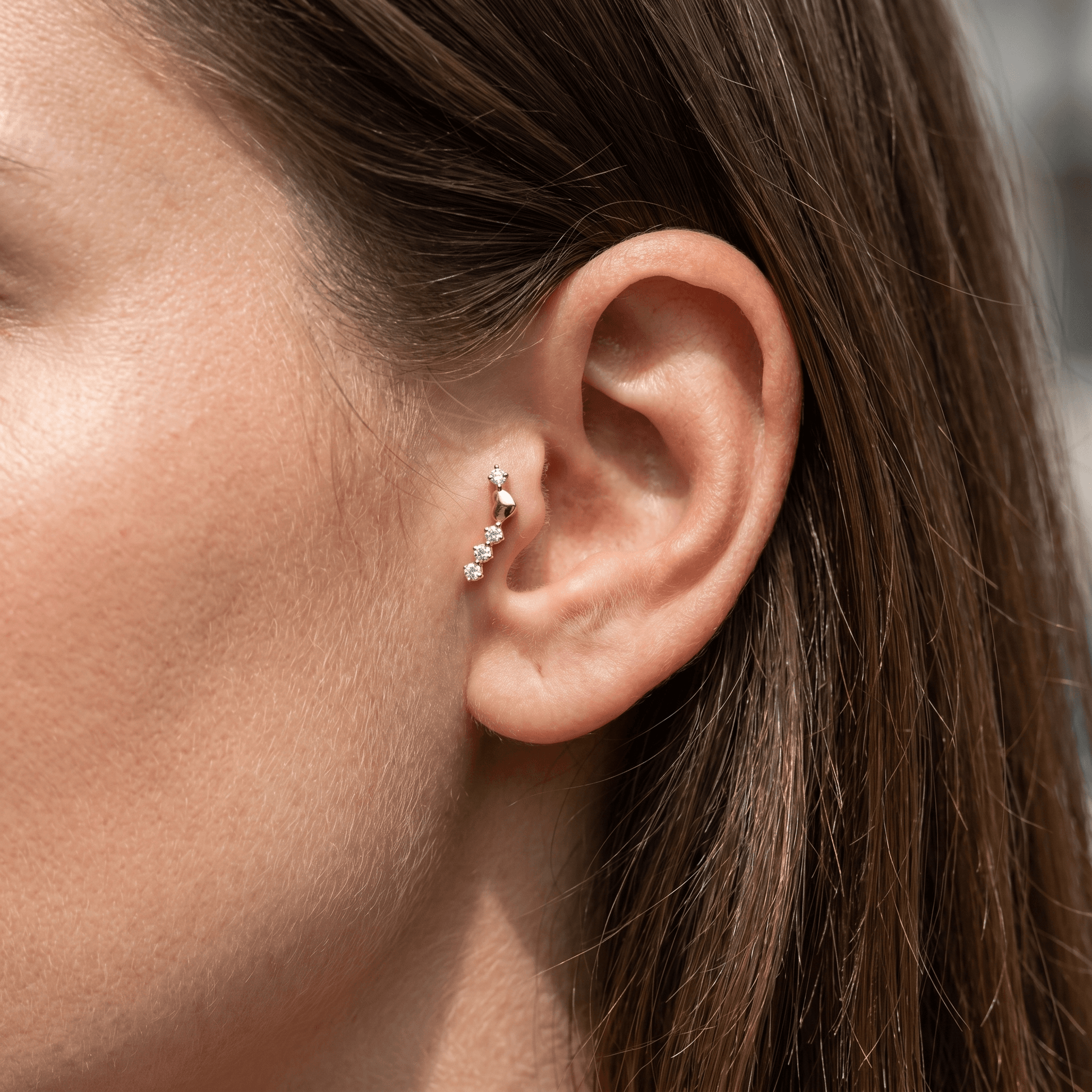 Gold titanium curved zircon piercing stud worn perfectly in a female piercing.