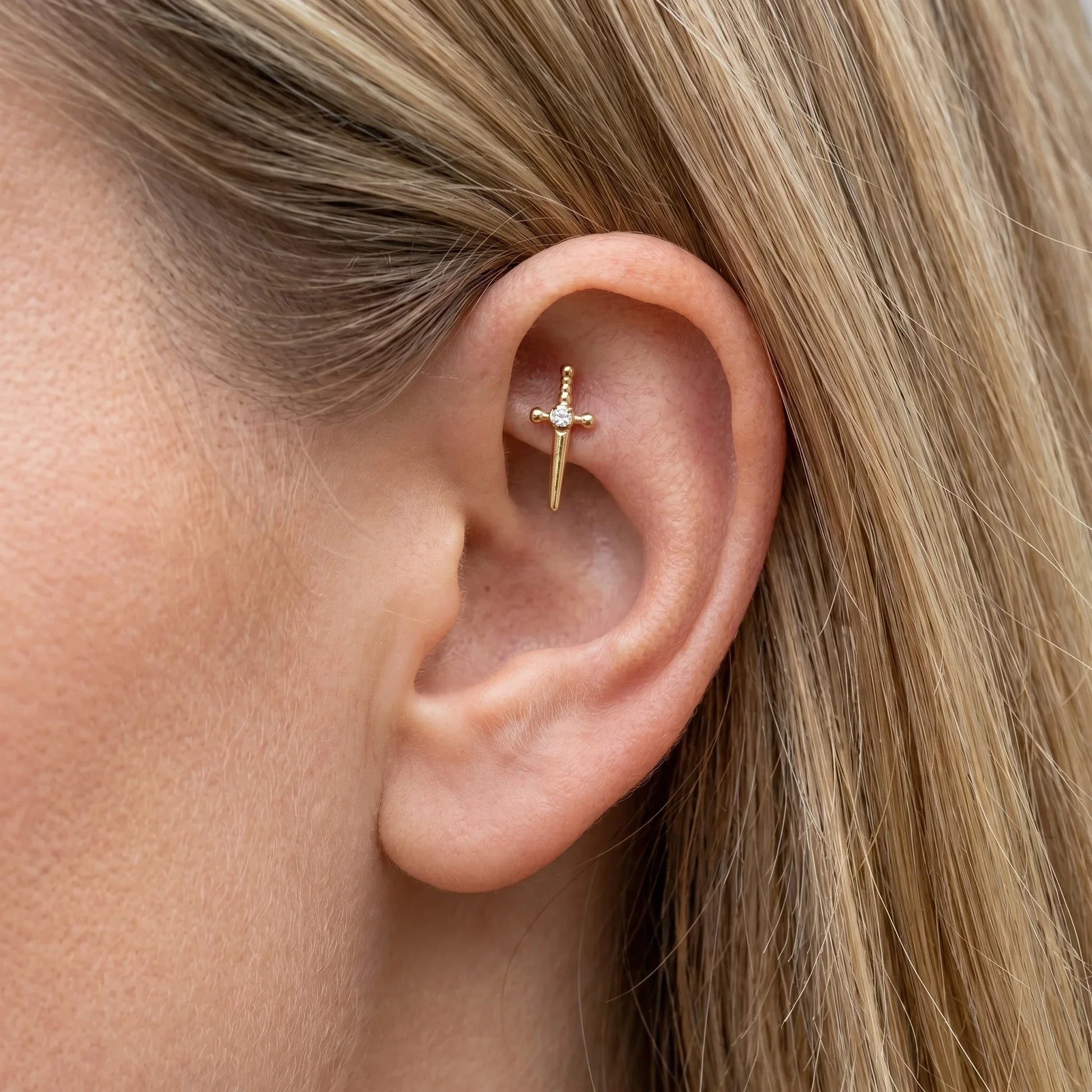 Gold medical-grade titanium stud worn gracefully in a faux piercing.
