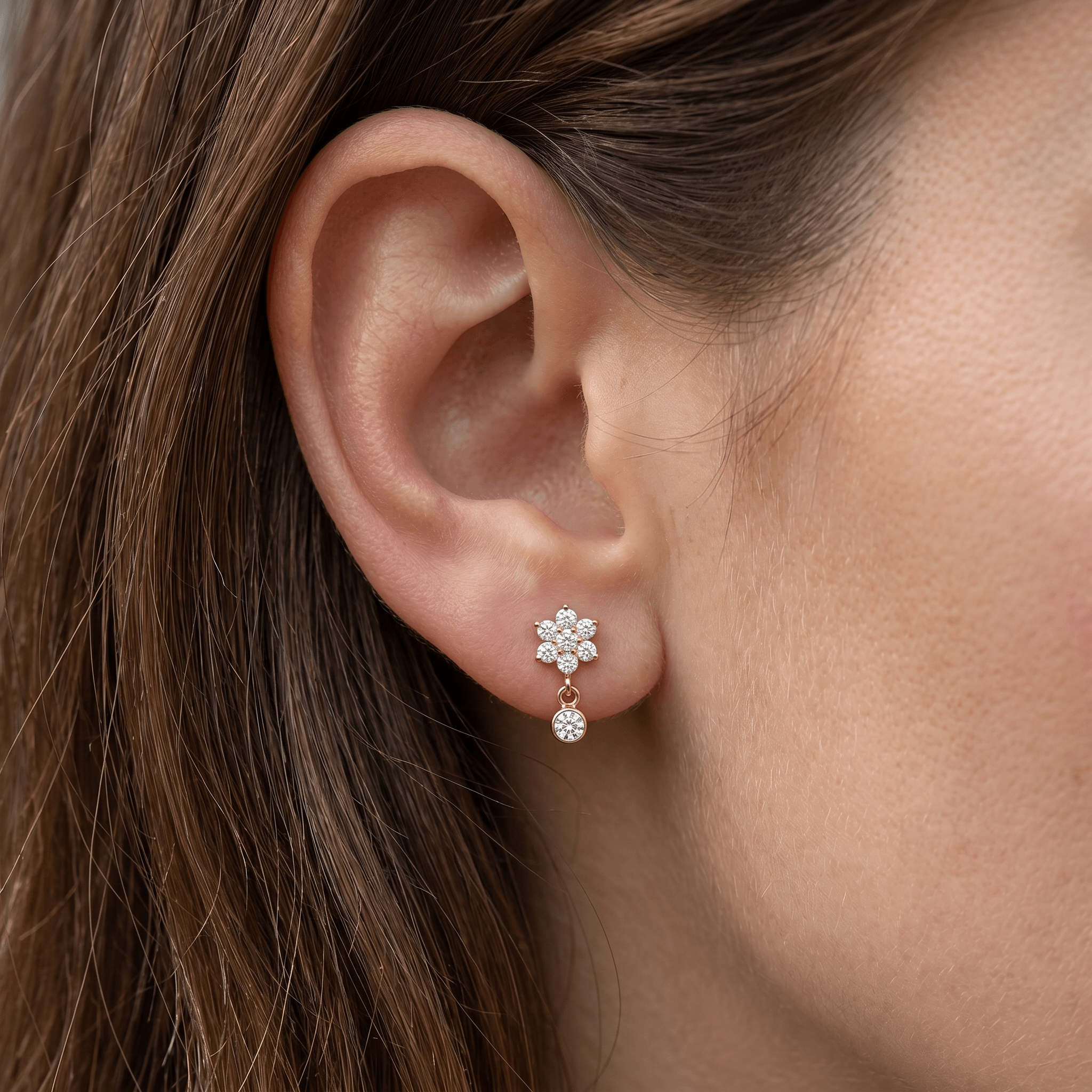 Gold daisy dangle titanium stud worn in a standard piercing.