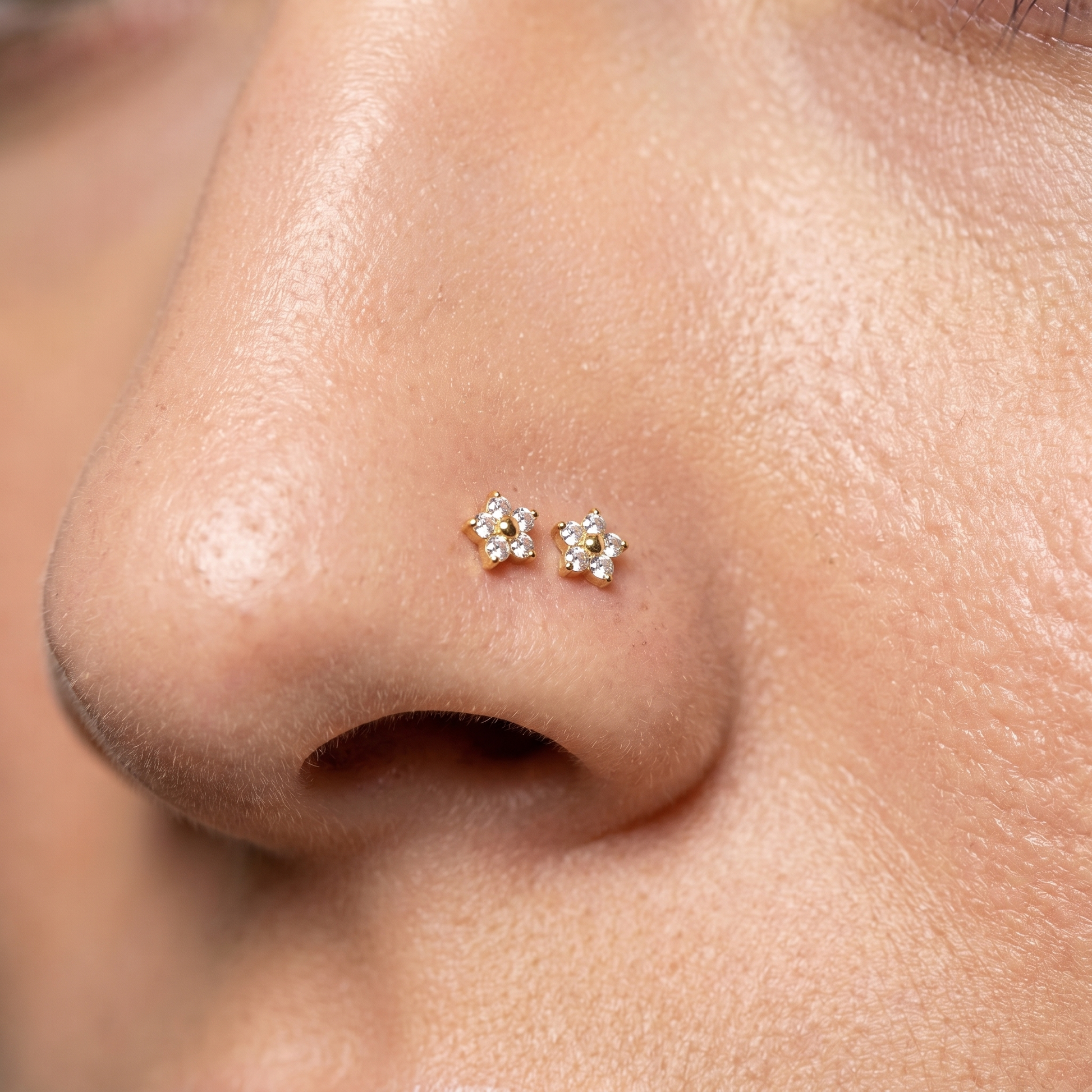 Two daisy nose studs styled as a double nose piercing on one nostril