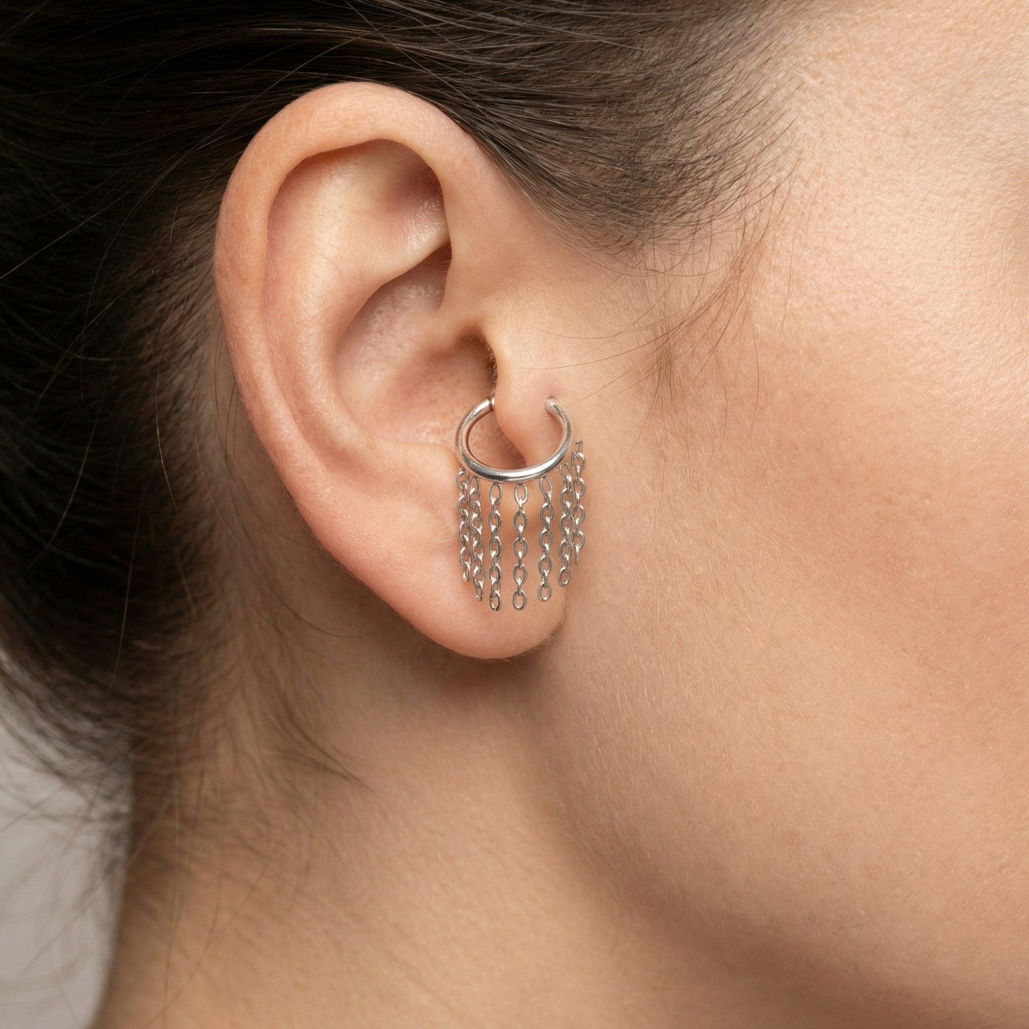 Silver dangling chain clicker hoop ring styled elegantly in a model's piercing.