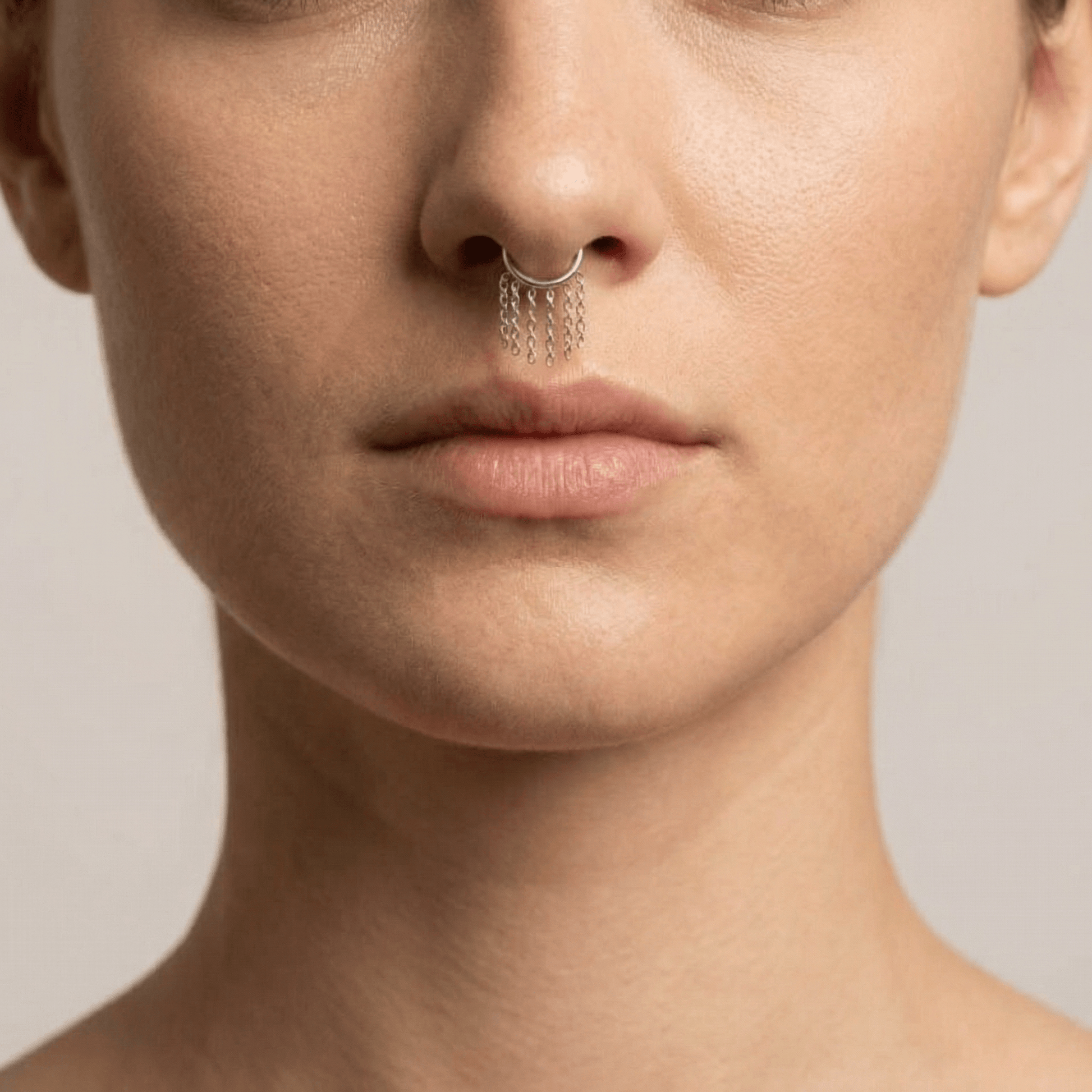 Model showcasing a silver dangling chain clicker ring styled seamlessly as a  septum nose piercing.