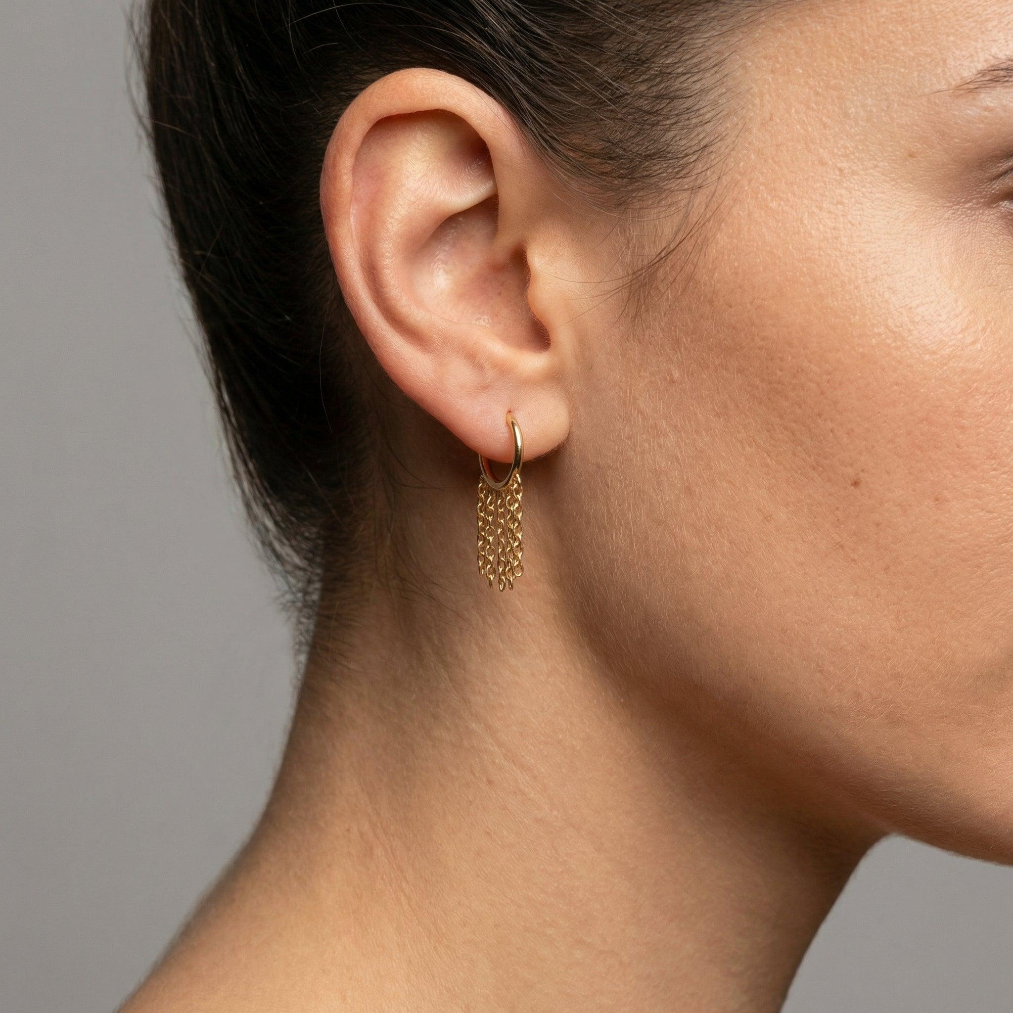 Gold dangling chain clicker hoop ring styled inside a model's standard lower