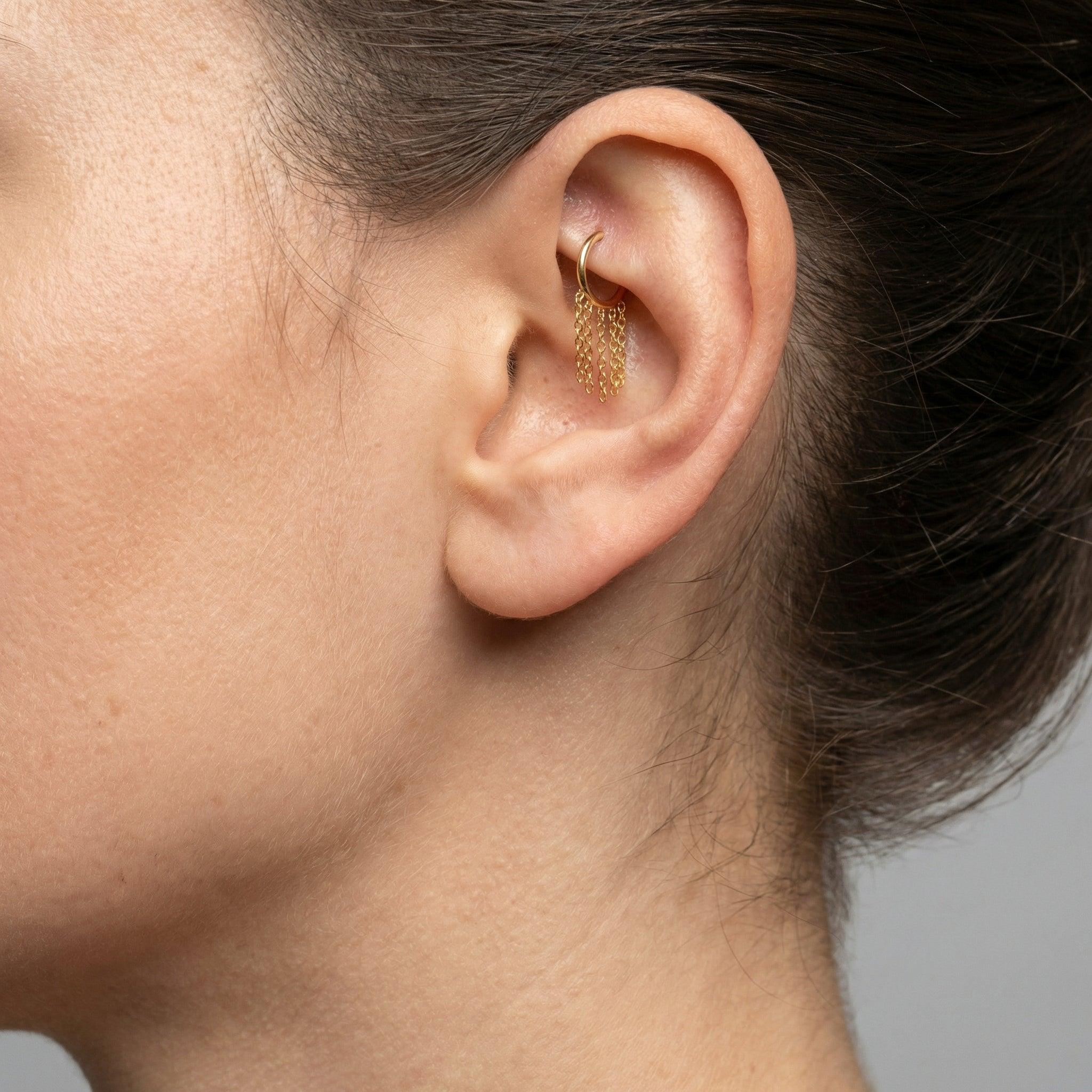 Gold dangling chain clicker hoop ring styled seamlessly in a faux piercing