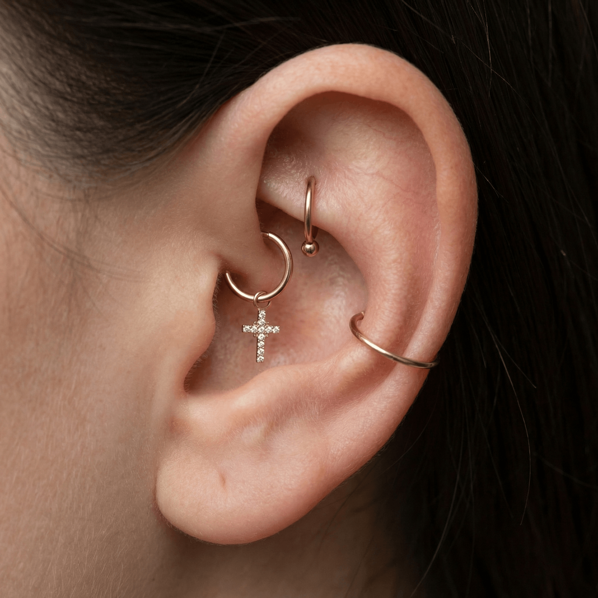 Close-up of gold cross charm piercing jewelry styled perfectly in a female