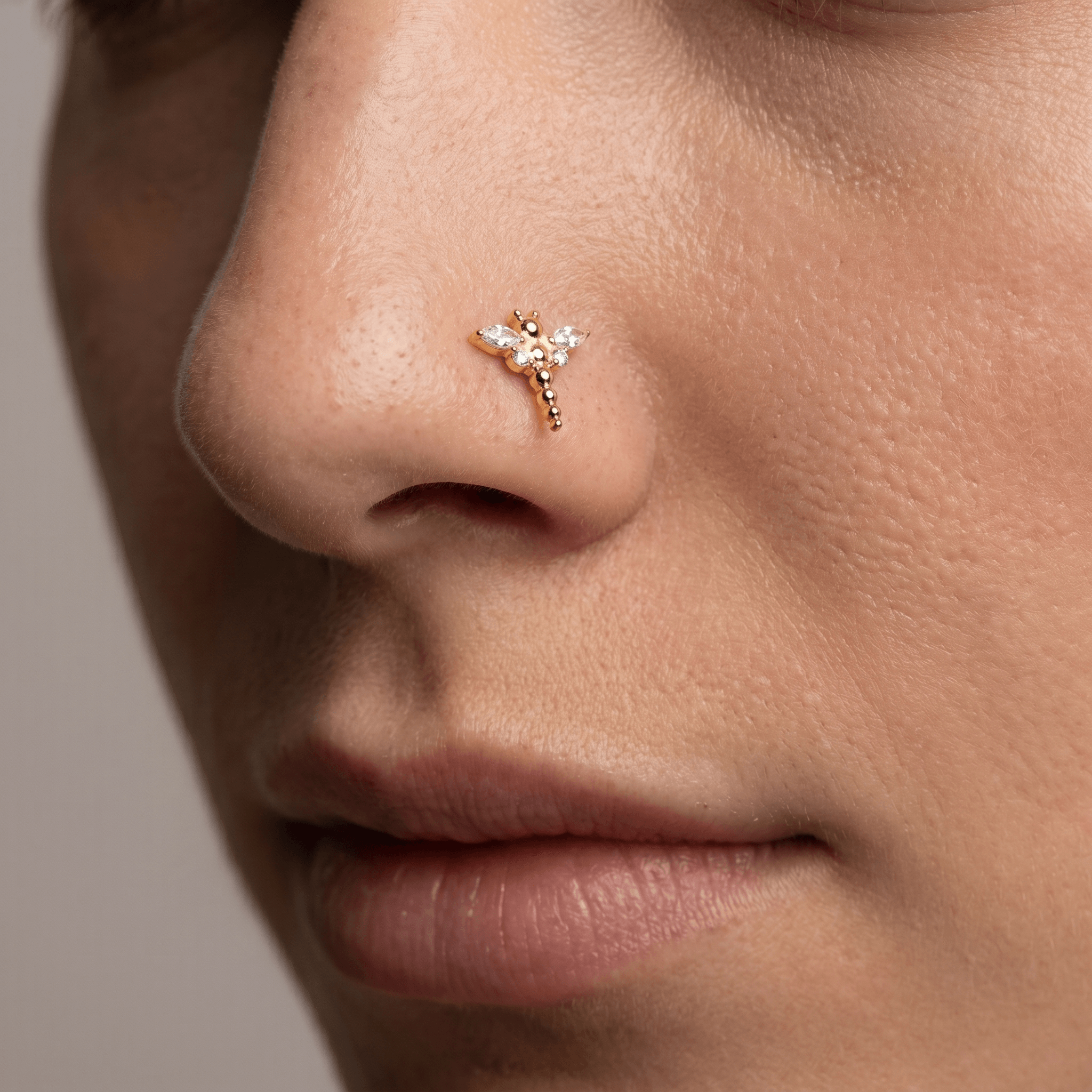 Gold dragonfly zircon stud worn gracefully as a piercing.