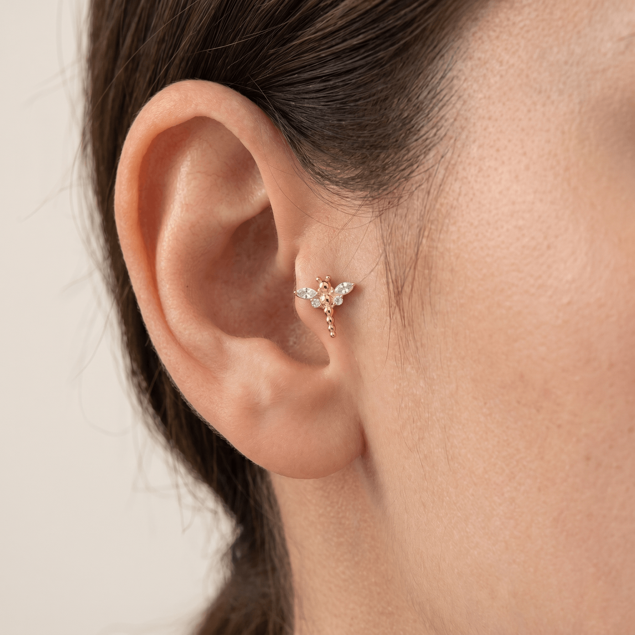 Gold dragonfly jewelry worn in an outer ear cartilage placement.